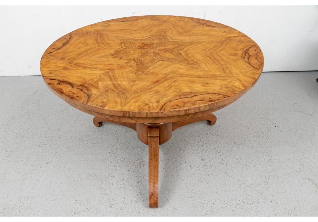 A handsome and very well crafted Period Biedermeier Center Table with fine traditional form. The table with particularly attractive book matched top forming a star motif in the center. Raised on a plain column support on three scrolled footed legs.