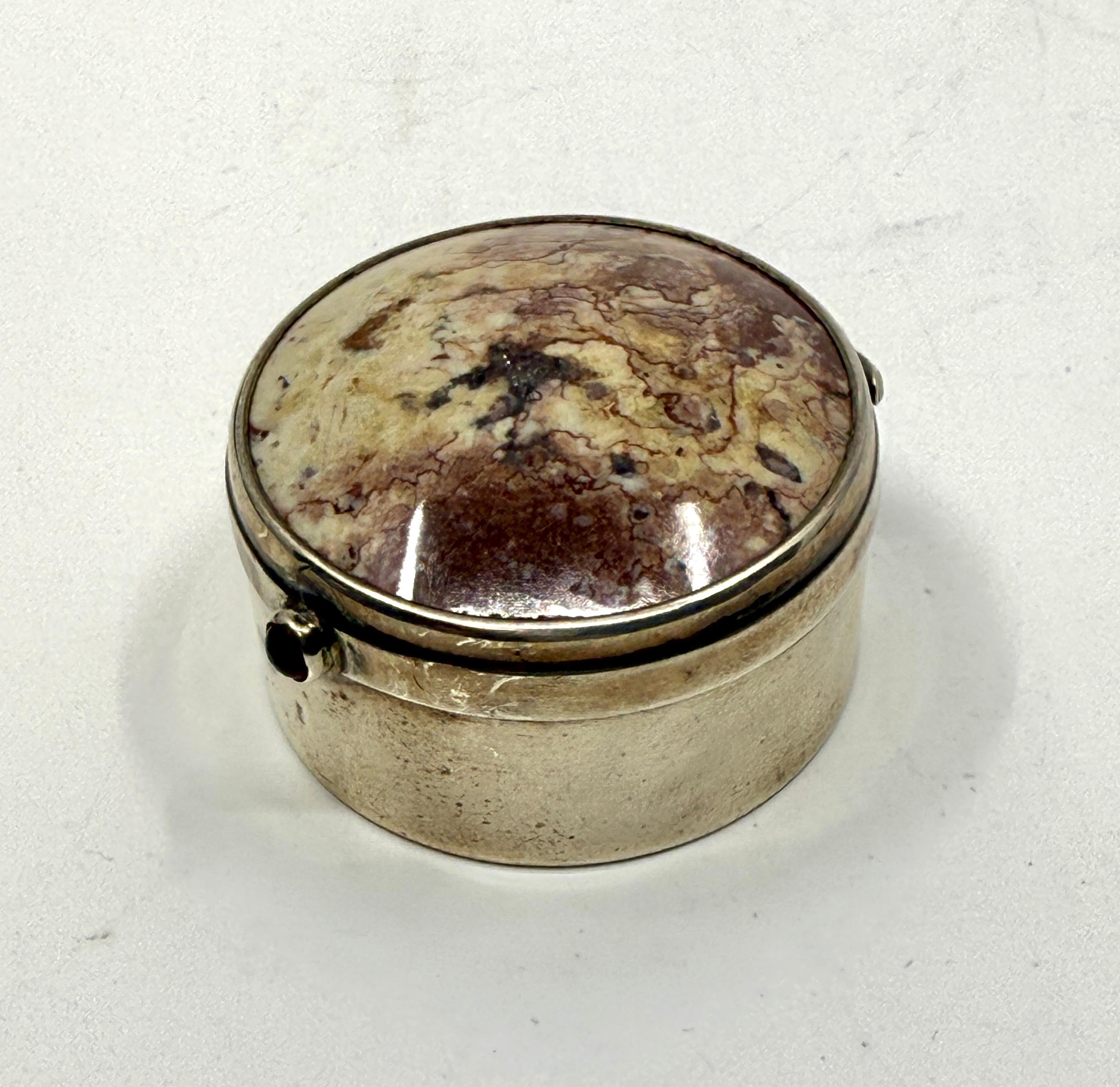 a beautiful little Birhimham Sterling Silver Pill box with an agate top. The The has a different color slice underneath on the interior. The outside is decorated with what I believe is a Cabochon Ruby. The sterling hallmark dates the box to 1912.