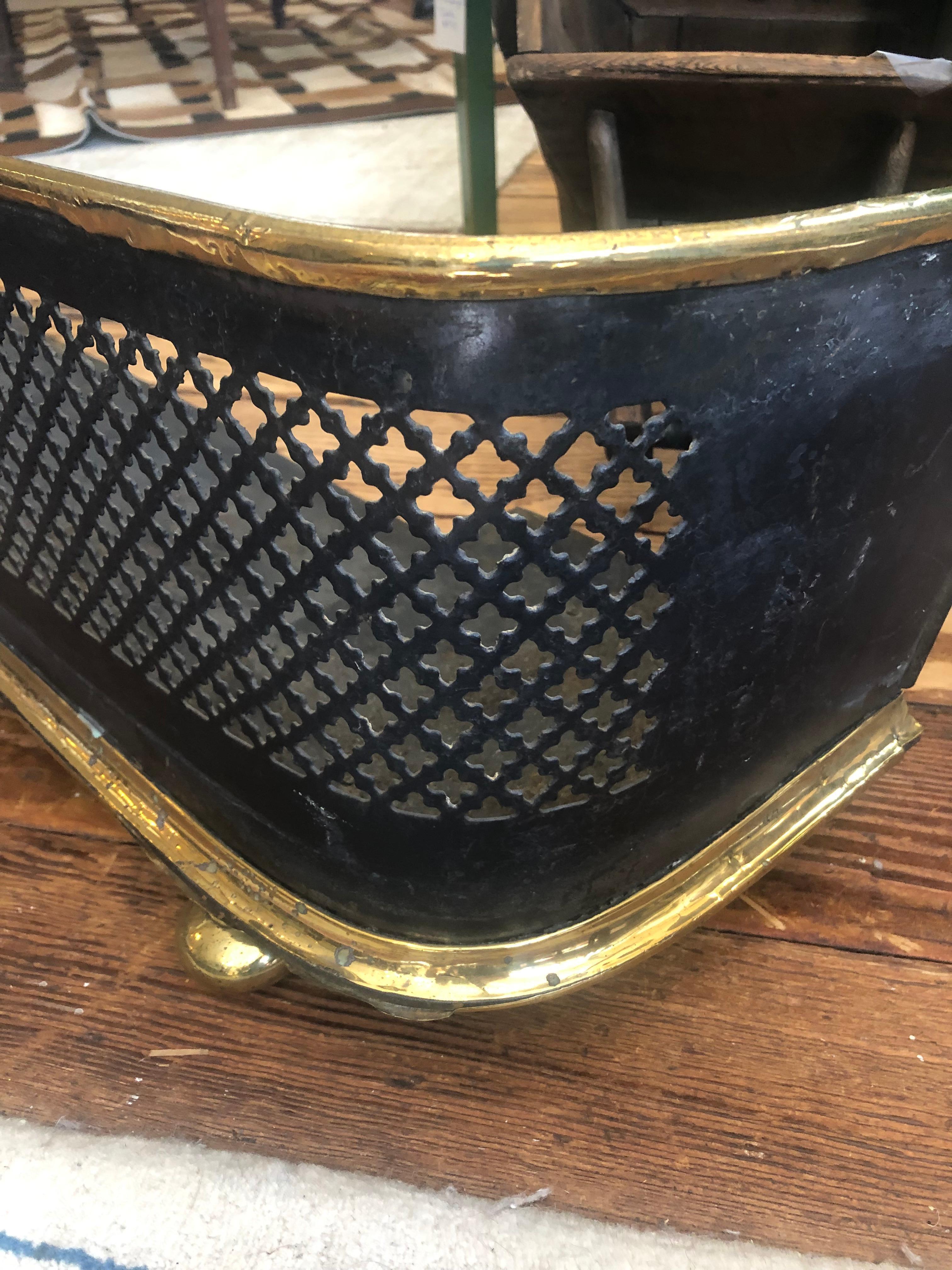 A long curved classic 19th century fireplace fender having black cut out body framed in handsome brass on brass feet.