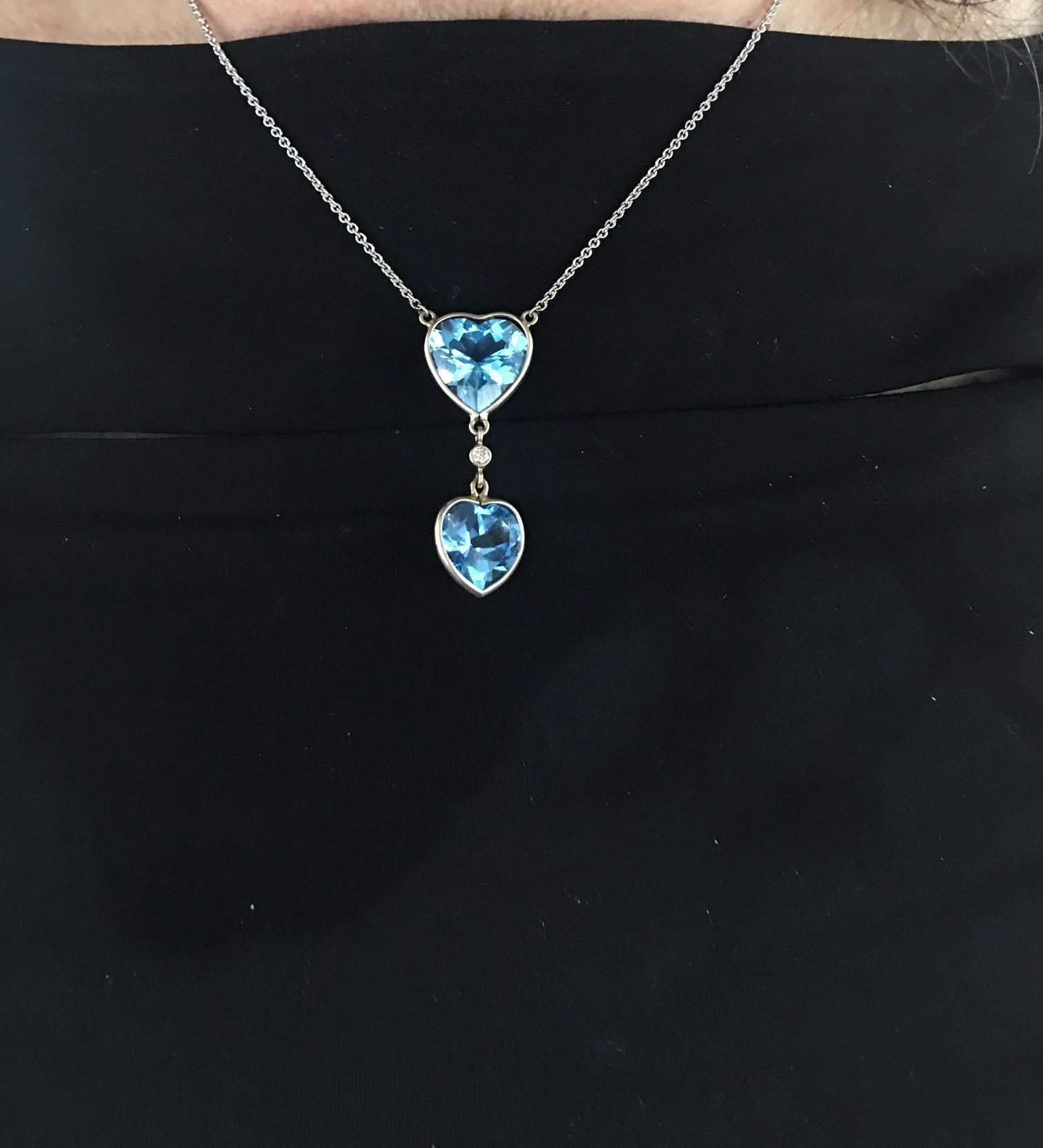 Simply Beautiful! Blue Topaz Hearts Gold Pendant. Suspending 2 Checkerboard facet-cut Blue Topaz Teardrop Hearts, measures approx. 15mm x 15mm and 28mm x 19mm. Centered by a round Brilliant cut Diamond; weighing approx 0.07 Carat. Hand crafted 14k