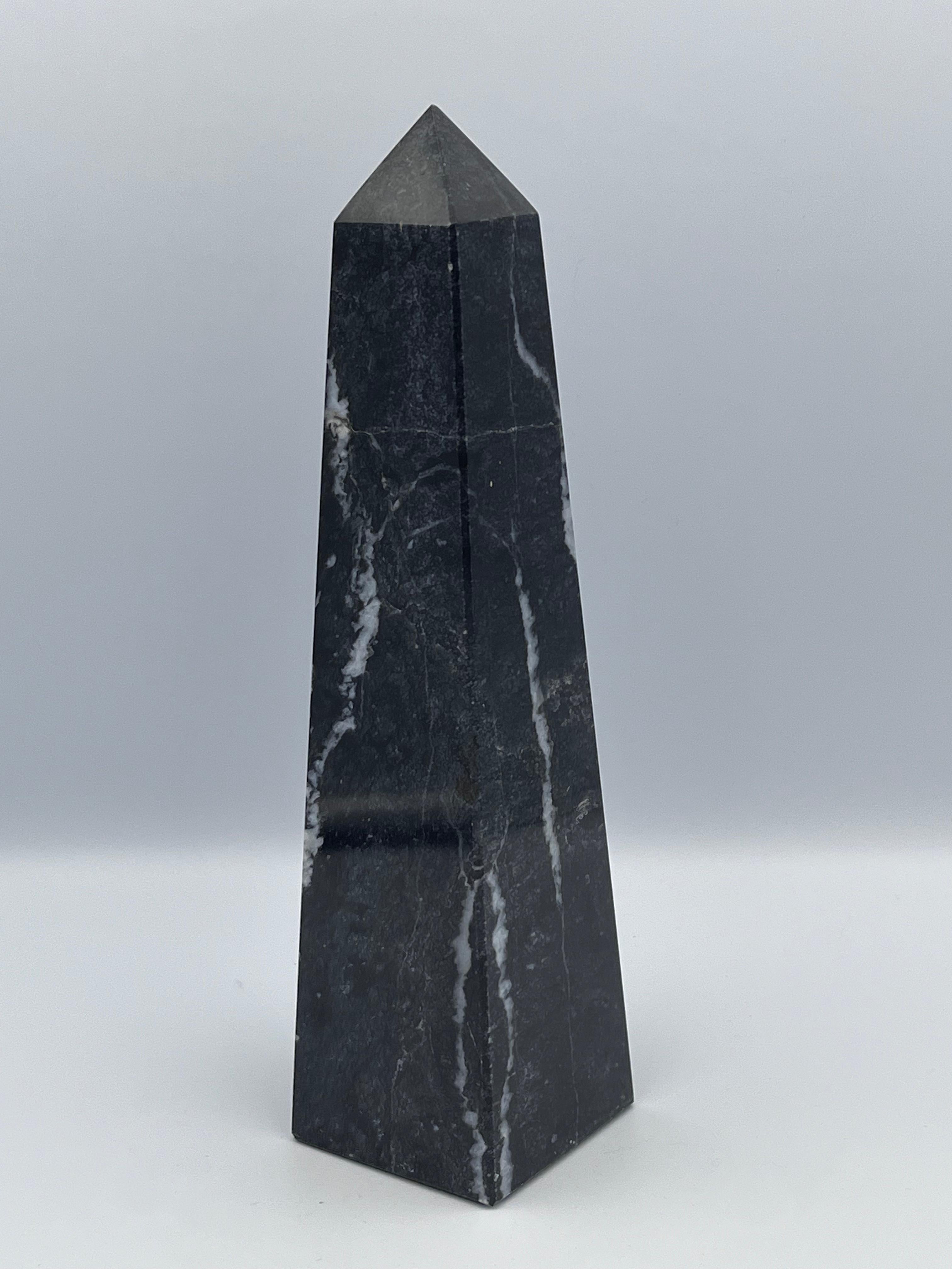 Élevez votre espace avec cet obélisque en marbre noir, fabriqué à partir de pierre solide et caractérisé par d'élégantes veines blanches sur toute sa surface. La forme géométrique intemporelle de l'obélisque est depuis longtemps associée au pouvoir,