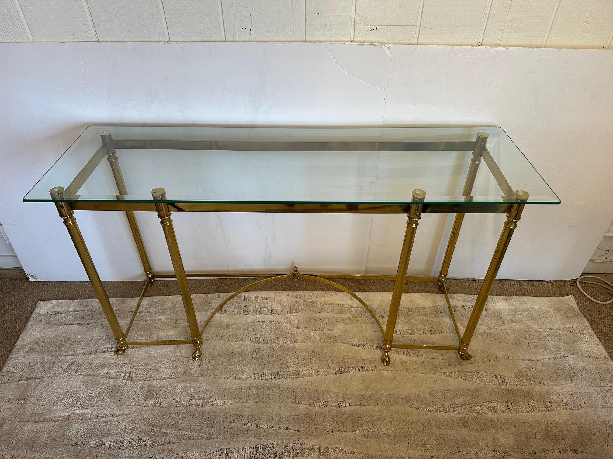 Mesa consola LaBarge de época intemporal con base clásica de latón con remates decorativos, bastidor y maravillosos pies de pezuña.
La parte superior es de cristal rectangular biselado.