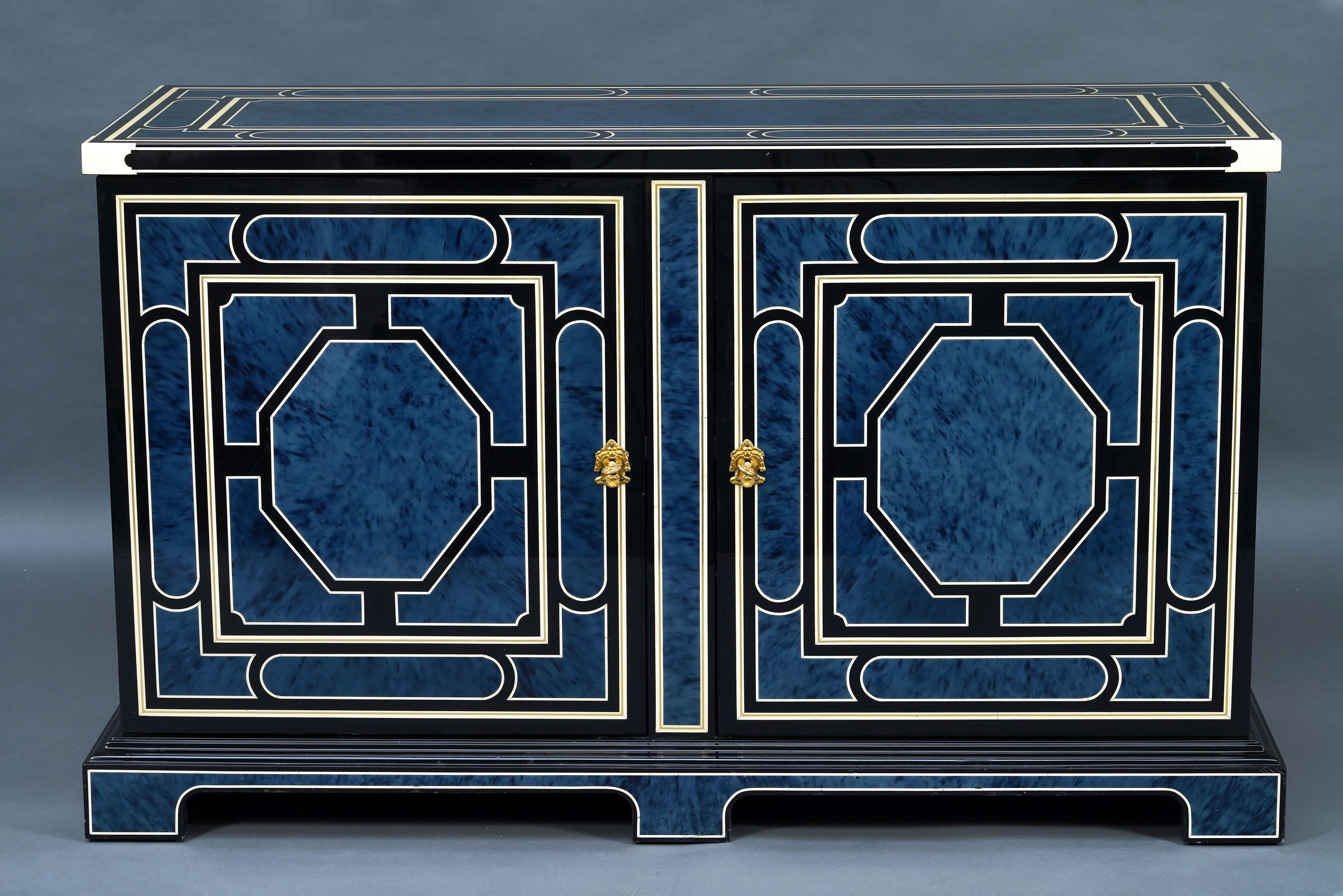 Beautiful lacquered wood buffet with lapis blue decoration simulating tortoiseshell in geometric frames composed of a double fillet, one imitating ivory and the other brass, all on a black background.
Opening on the front with two doors revealing a