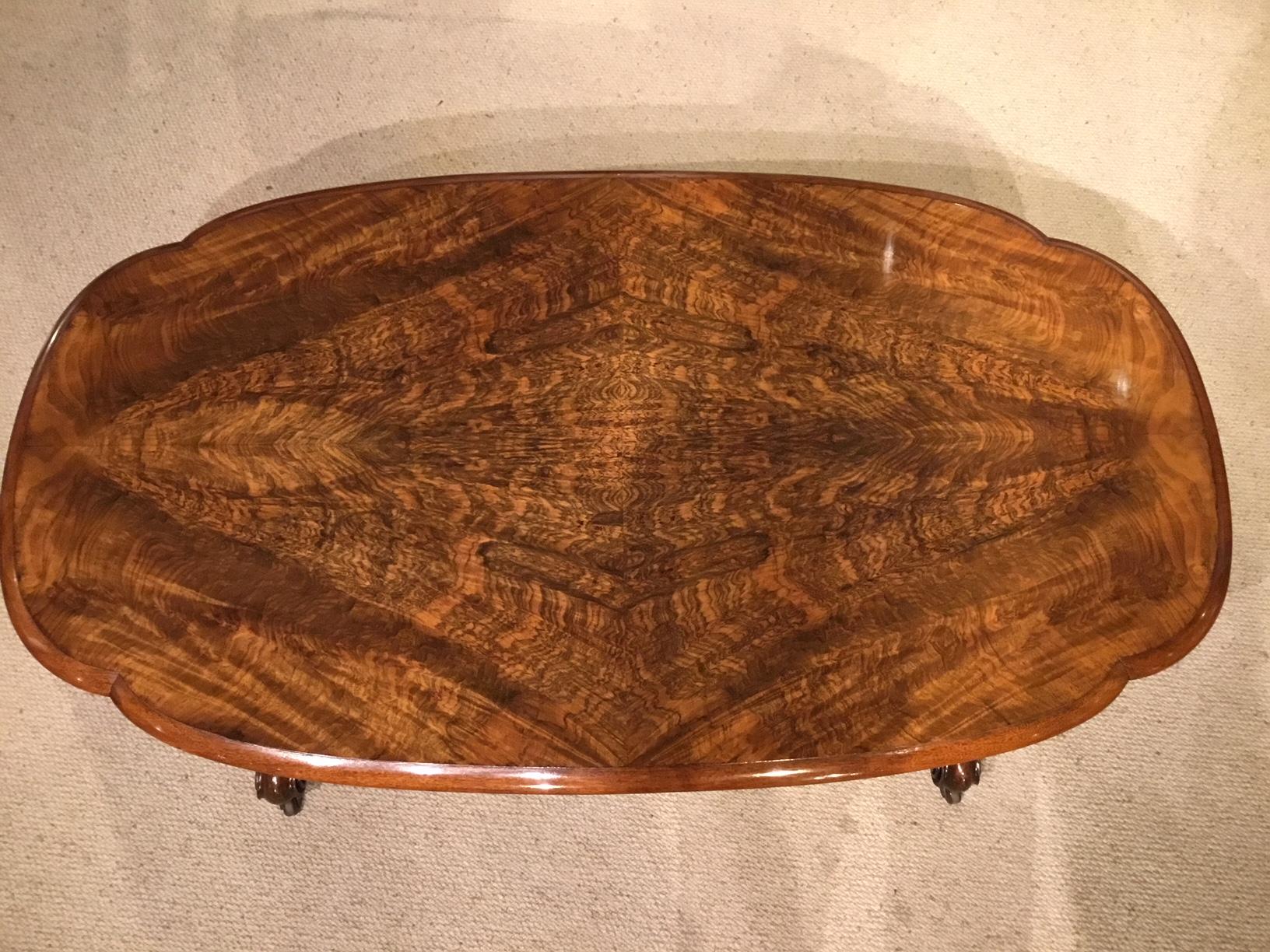 A beautiful burr walnut Victorian Period antique coffee table. Having an oval top veneered in beautifully figured burr walnut with walnut moulding and frieze. Supported on four turned and fluted columns with finely carved floral detail and a central