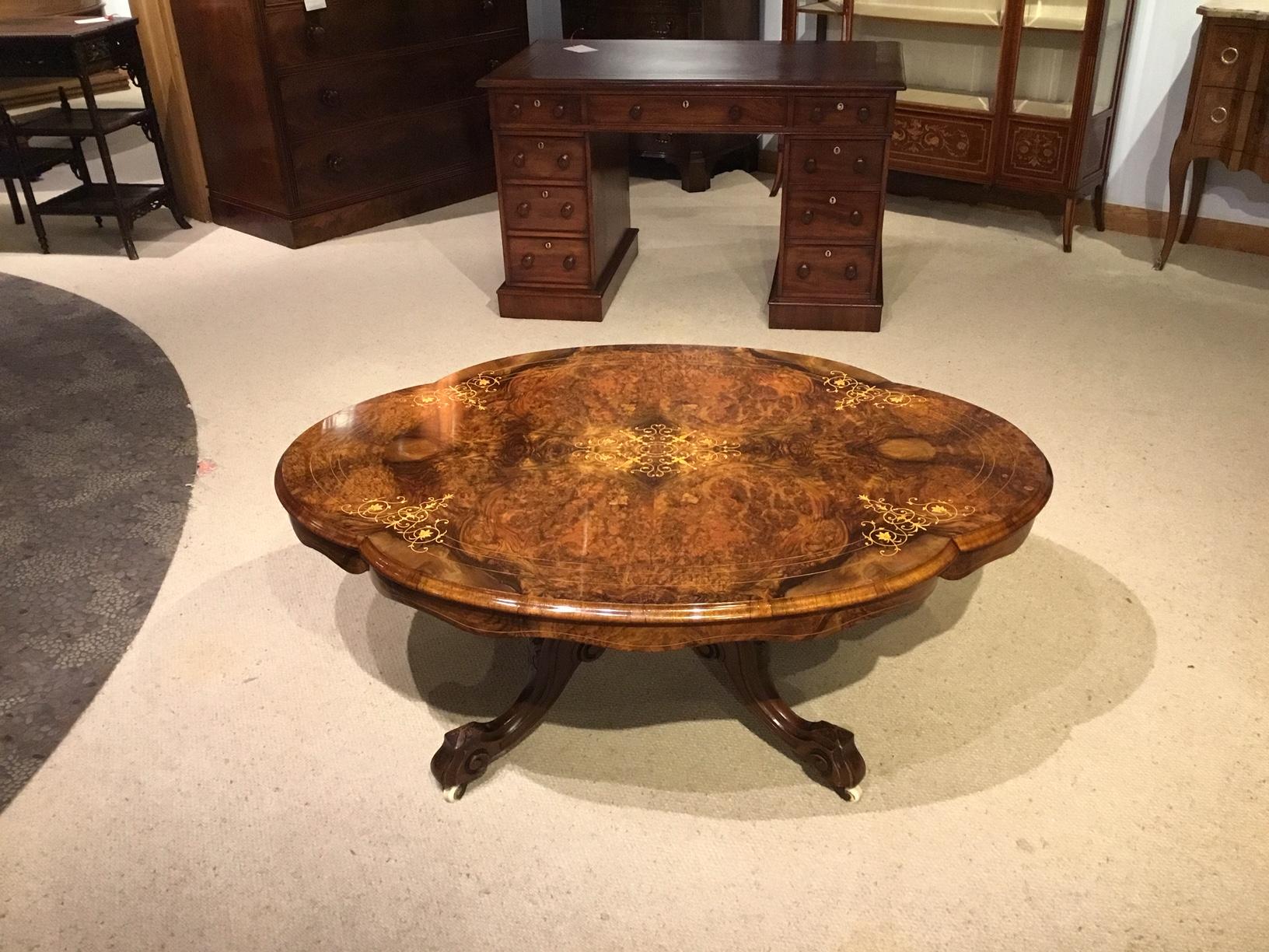 A beautiful burr walnut Victorian period shaped coffee table. Having a shaped top veneered in finely figured burr walnut with a fine marquetry boxwood inlaid floral motif to the centre and further inlaid detail to the border with a shaped wavy