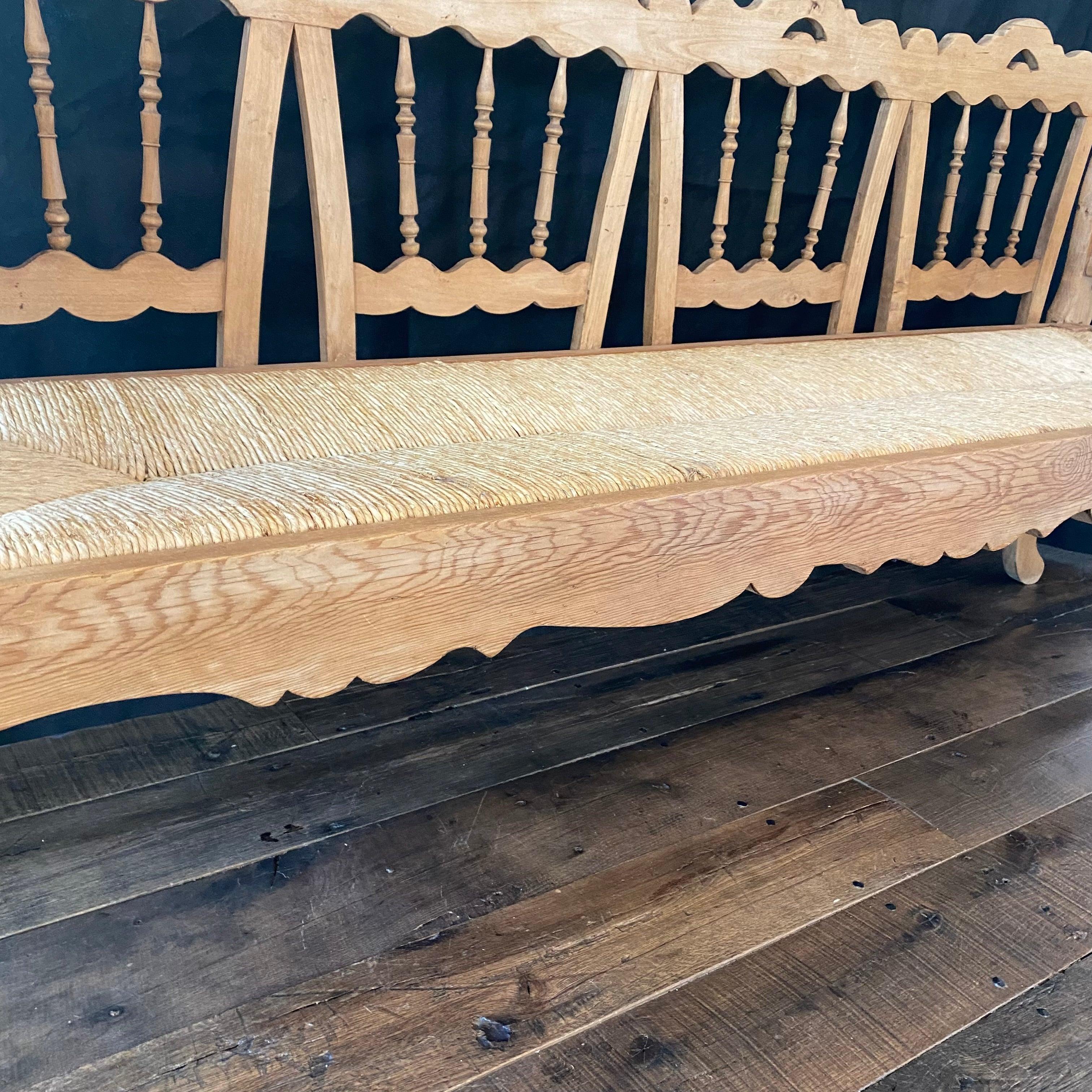 Carved pine settee or bench with elegant and graceful lines having open work backrest with carved patterns over a fluted apron, all resting on classic tapered cabriole legs. We love the swan shapes on the front. Original rush seat cushion in great