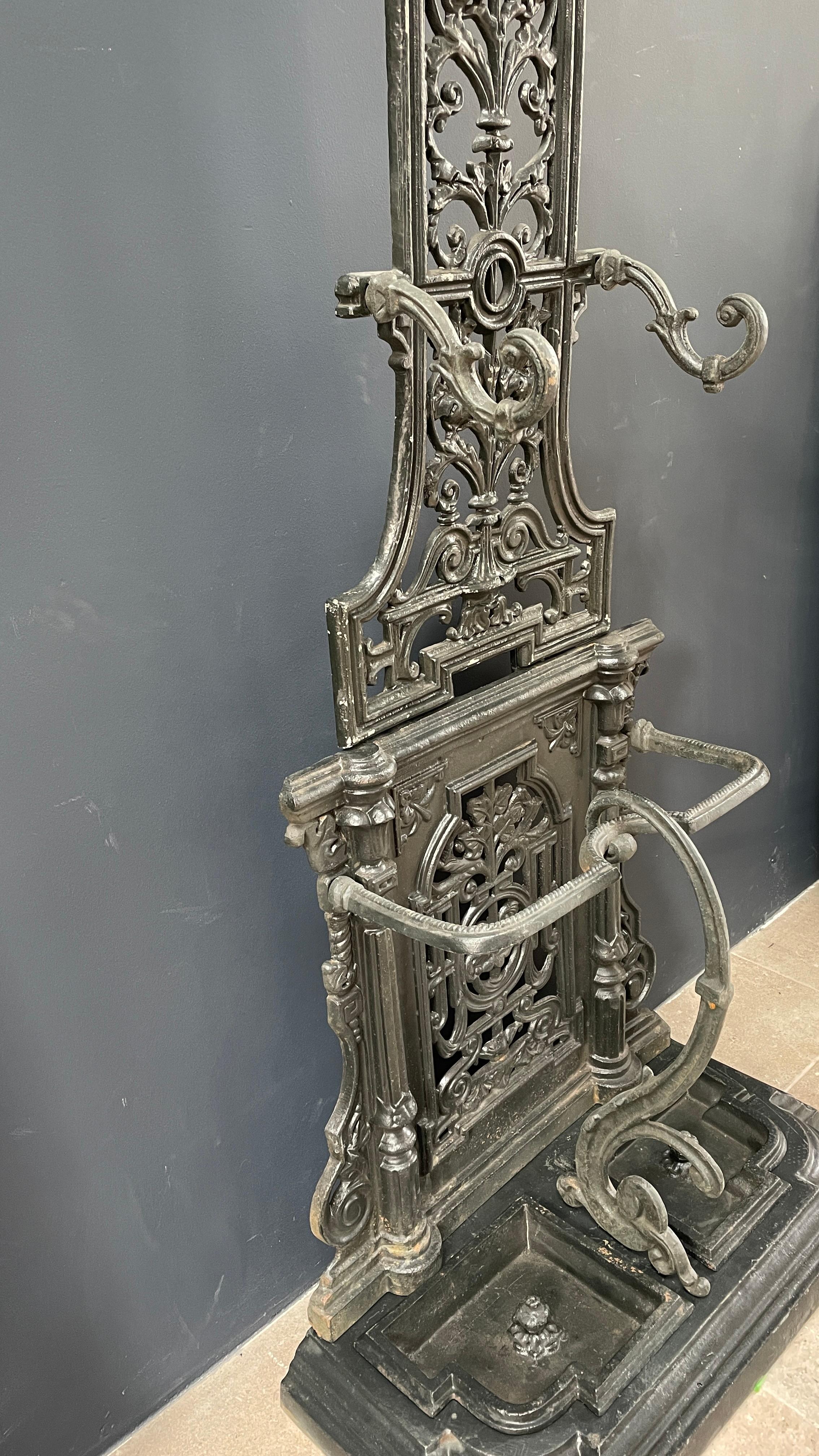 Beautiful coatrack or hat stand. This English rack is rich in detail and have a great patina. The top has hooks to put your coats on, the bottom has 2 umbrella stands with detachable cups to collect the draining water. This can be a great addition