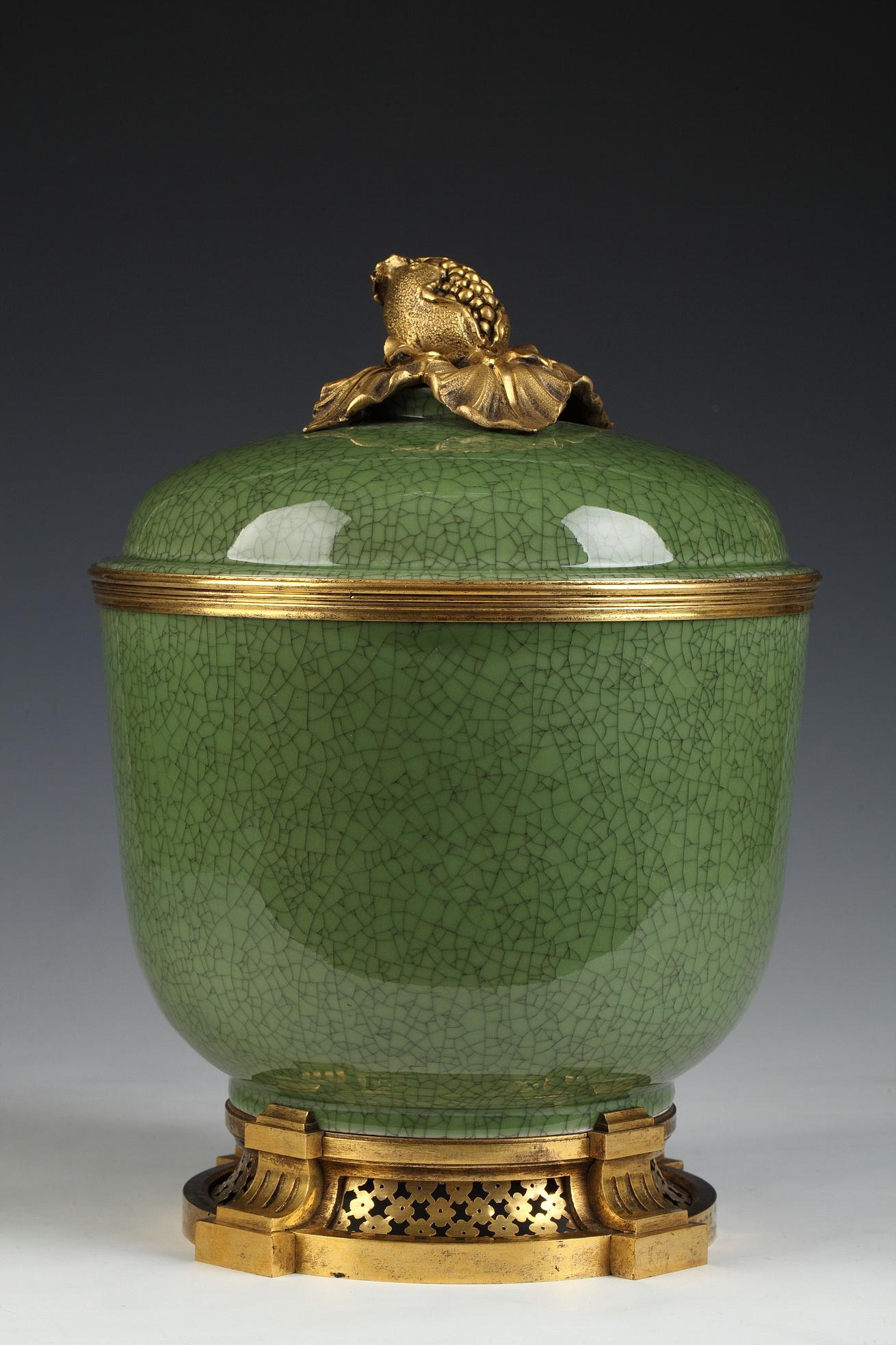 Celadon porcelain jar with gilt-bronze mounts attributed to l'Escalier de Cristal. The jar relies on a gilt-bronze base with four ribbed consoles joined by open-work wire nets on a large moulding. A gilt-bronze circle separates the body from the