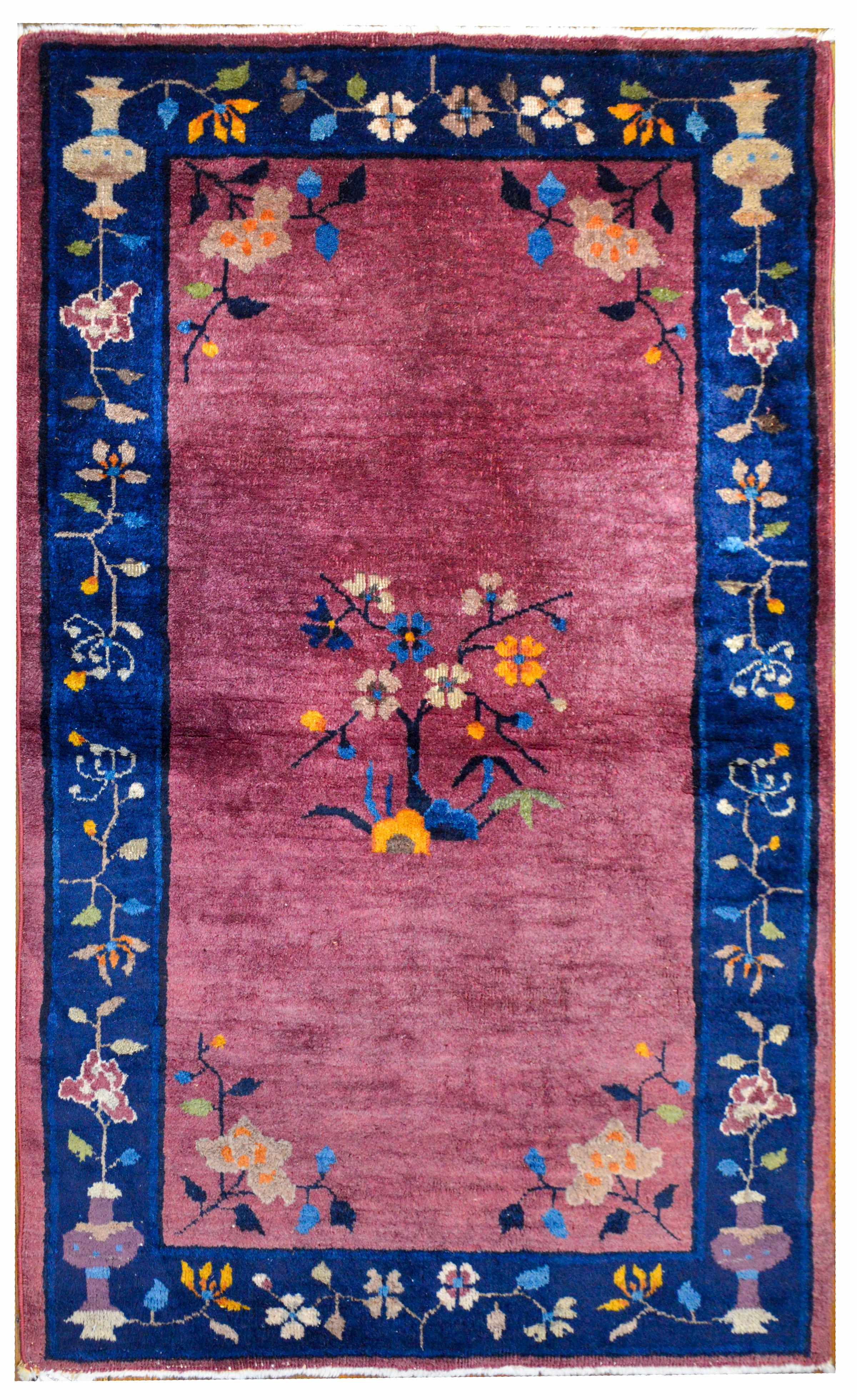 A beautiful early 20th century Chinese Art Deco rug with a rich lavender field surrounded by a wide indigo stripe border. The field features a blossoming cherry blossom tree in the center with a peony in each corner, surrounded by a cherry blossom
