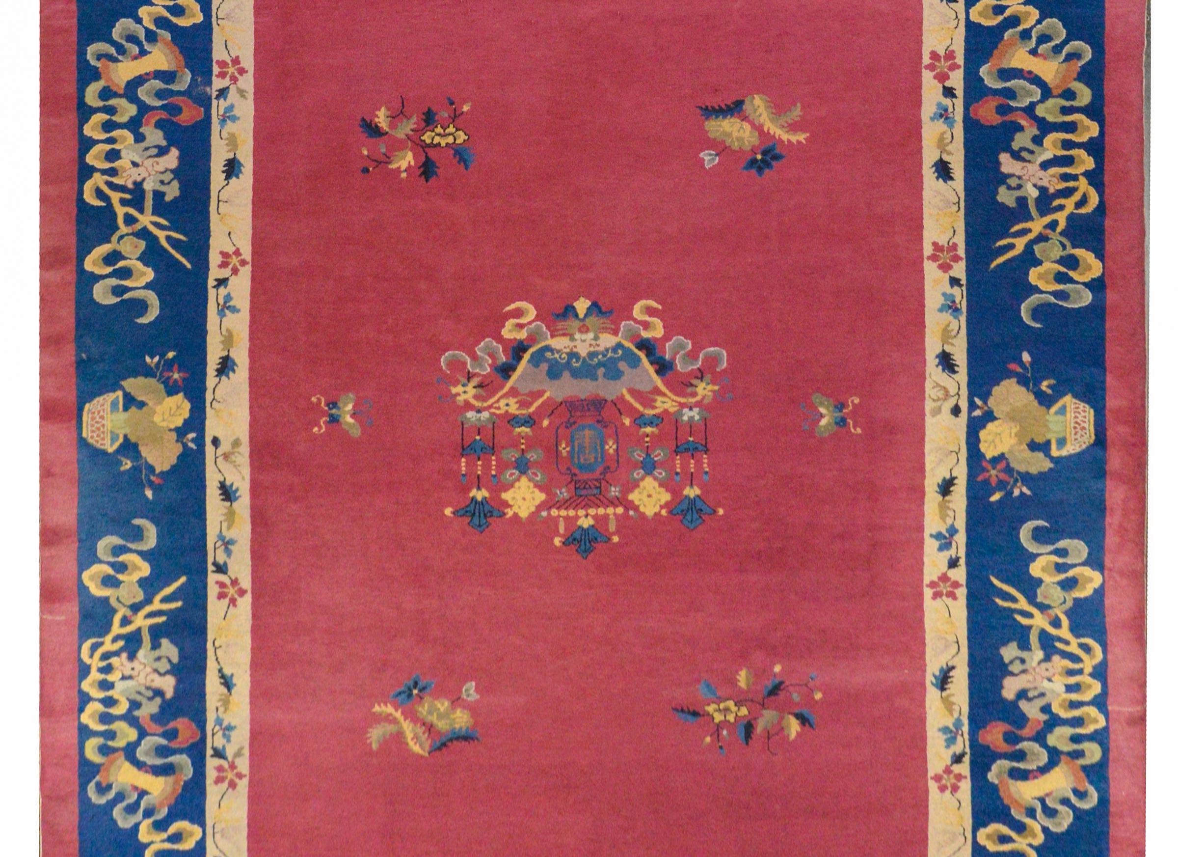 A beautiful early 20th century Chinese Art deco rug with a cranberry field with multi-colored hanging lanterns surrounded by a wide indigo and narrow cream colored border with auspicious flowering plants and Fu characters, symbols of good fortune.