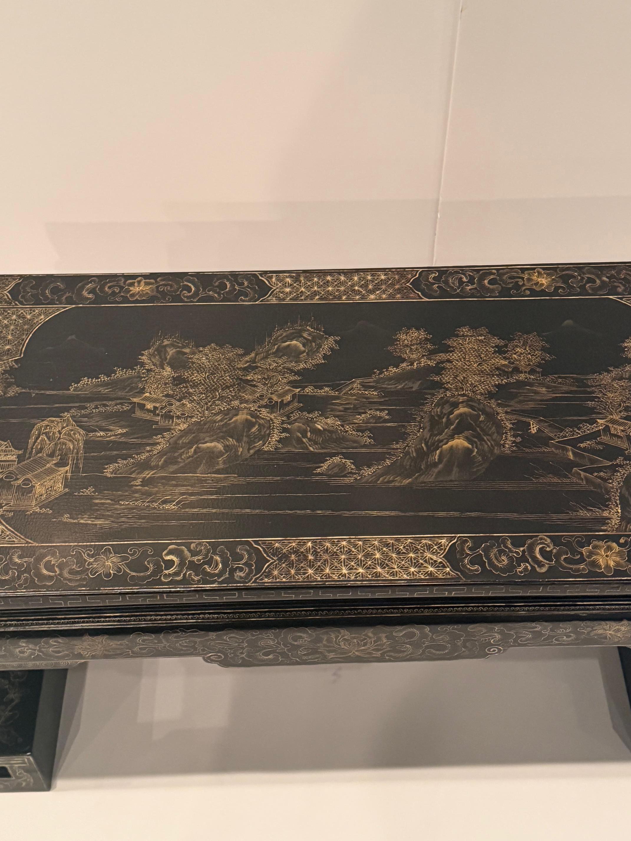 Magnifique table basse de style oriental, laquée noir, ornée d'un paysage détaillé en or.  Les pieds sont merveilleusement façonnés avec un style chinois.

RR