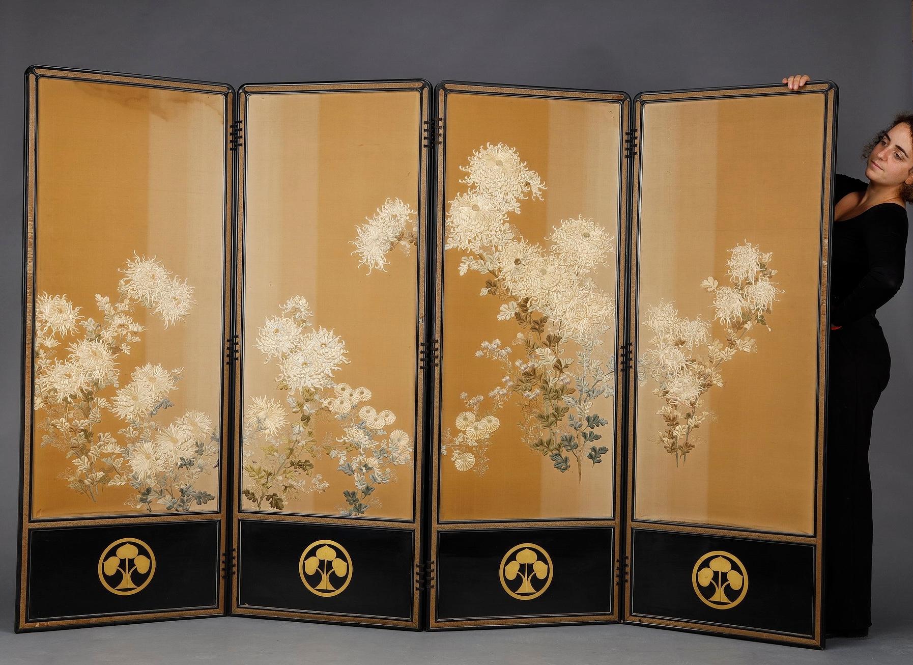 Very large four-leaf folding screen with black lacquered wooden frame, featuring the Honda clan coat-of-arms (Kamon) at the bottom. The panels are adorned with a very delicate wild silk fabric embroidered with a floral design featuring bouquets of