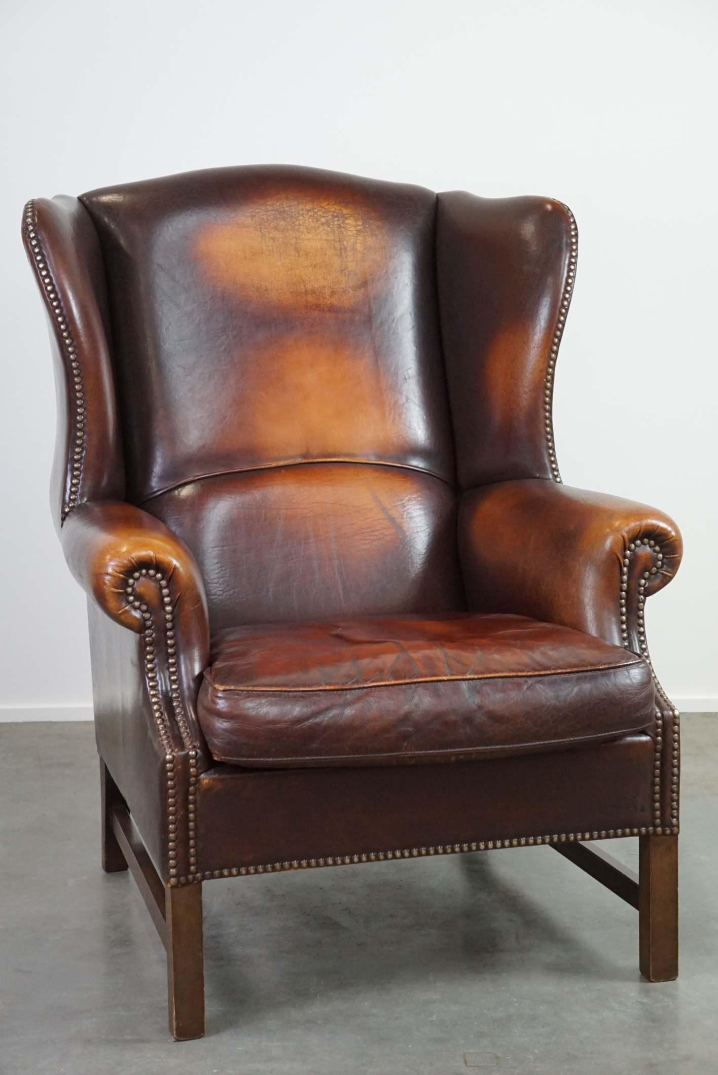 Offered: this beautiful classic and stately wingback armchair made of sheep leather with lovely colors and a timeless appeal.

This armchair is in good condition, with only a few normal signs of use, and boasts a luxurious and timeless appearance.