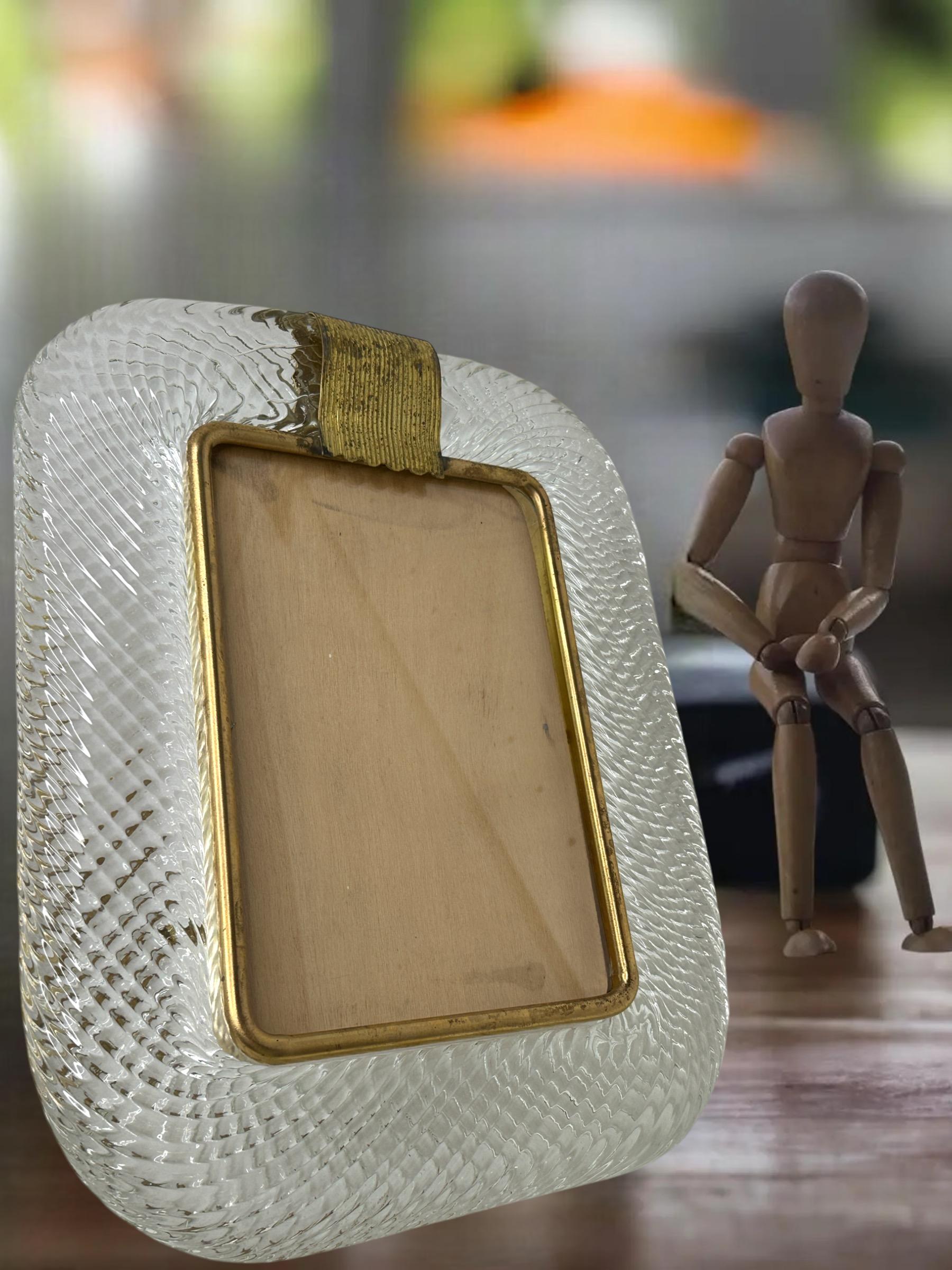 A gorgeous Murano art glass photo frame by Barovier & Toso, Murano, Italy, circa 1960 or older.  Made of clear glass with bronze brass liner and easel. Original marked on stand like seen in pictures. Original wooden back and photo glass included. No