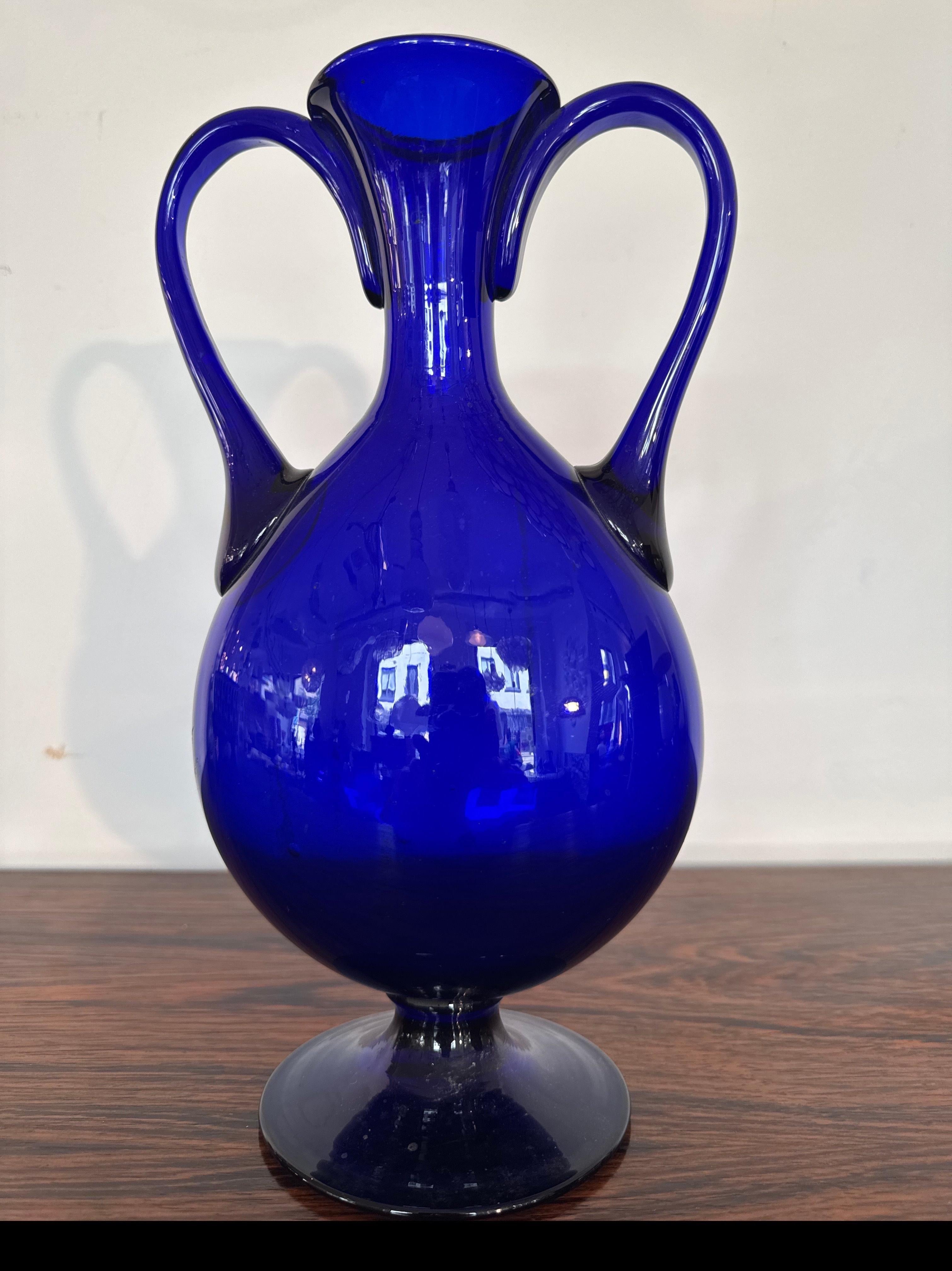 Beautiful cobalt blue Murano vase 1950s mouth-blown with hand-formed glass handle on either side based on a classic antique model. The vase is in a very good original condition and  a fascinating glass object, achieved through the craftsmanship and