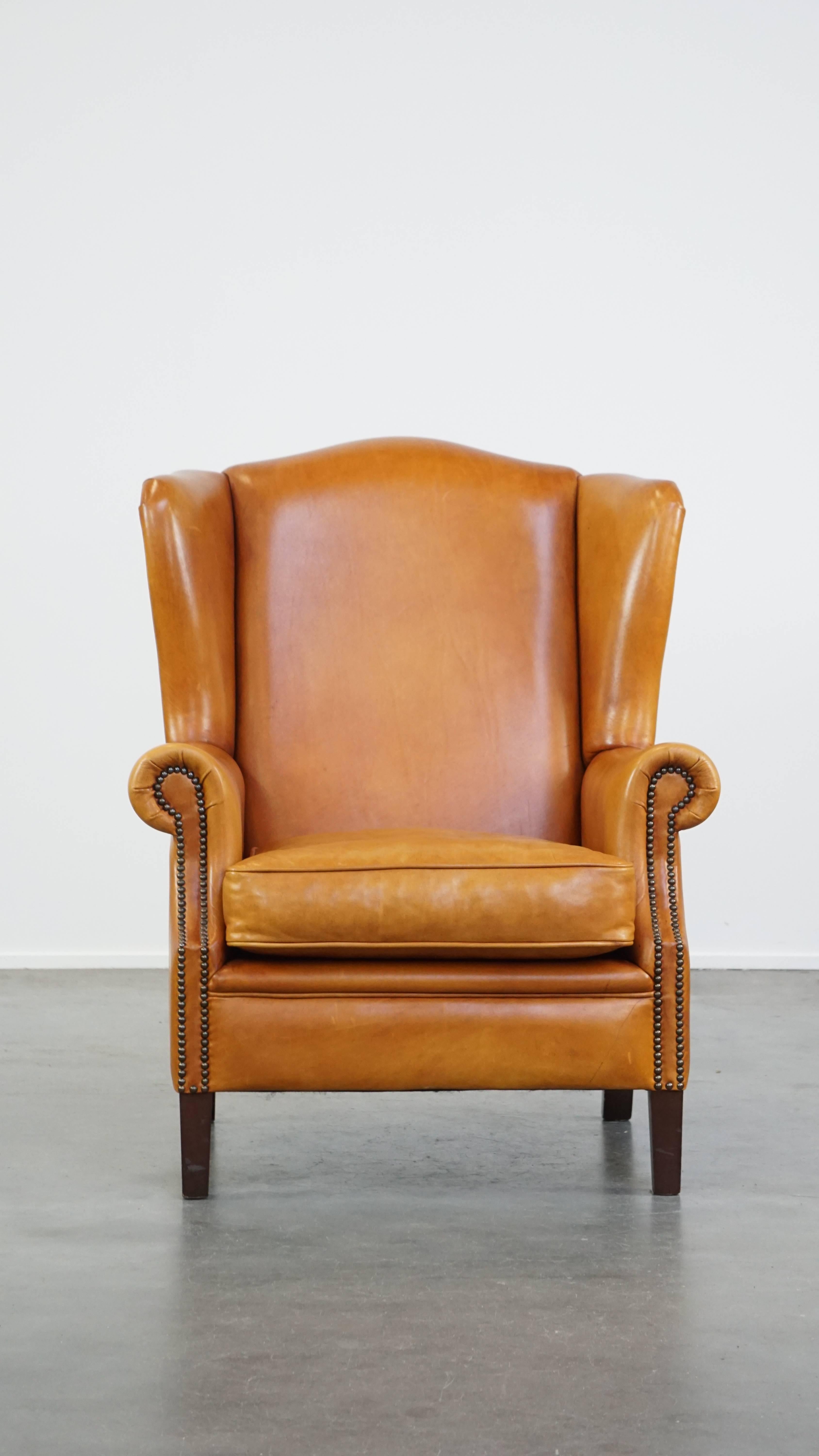 Ce superbe fauteuil à oreilles, en cuir de vachette, respire le luxe. Il est fini par des clous décoratifs et, grâce à sa couleur et à son design intemporels, peut facilement s'intégrer dans presque tous les intérieurs. Le fauteuil est doté d'un