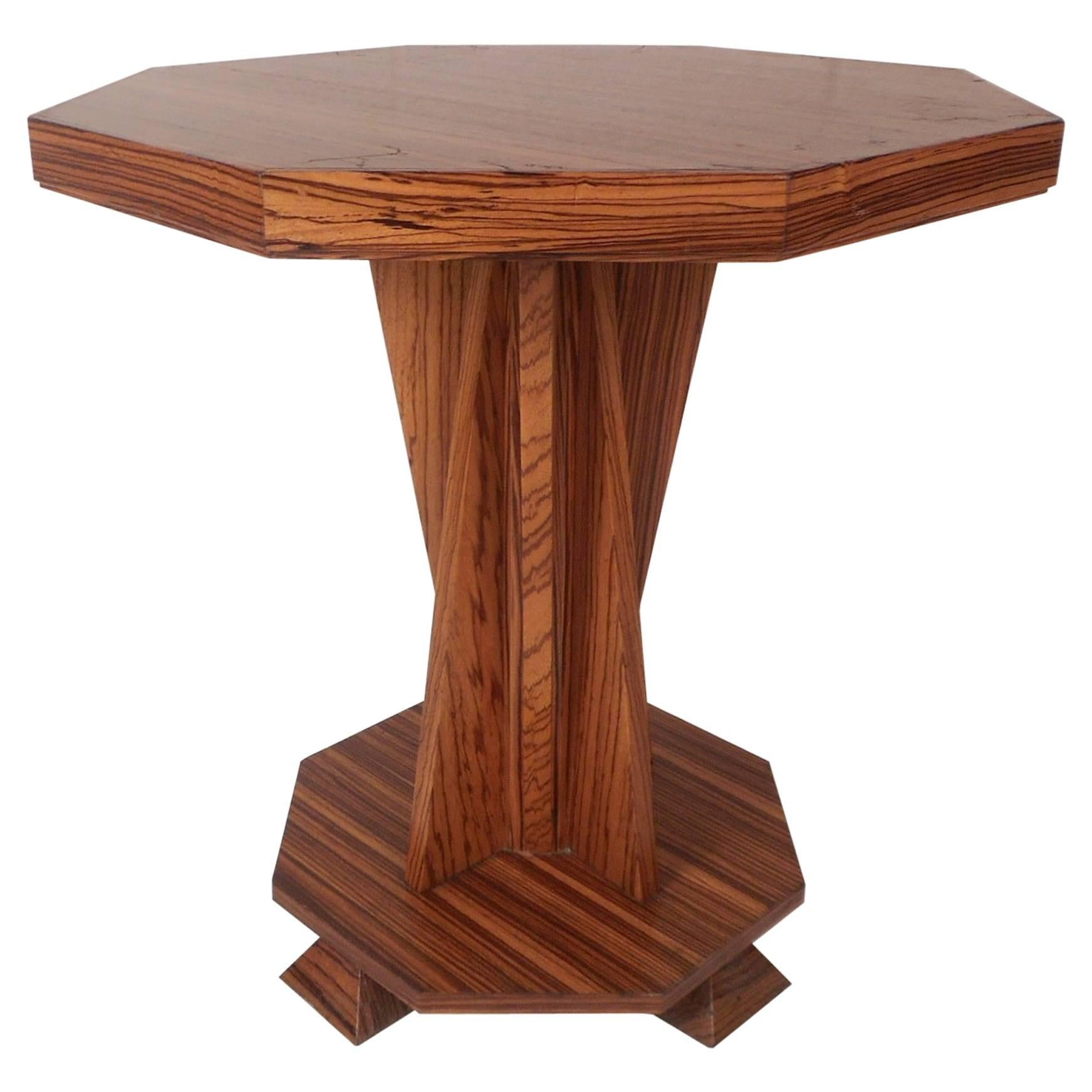 This beautiful custom-made table features a sculpted pedestal base with four trapezoid shaped feet. An excellent design with an octagonal base that can be used for added storage. This handmade end table has angled wood running vertically down the