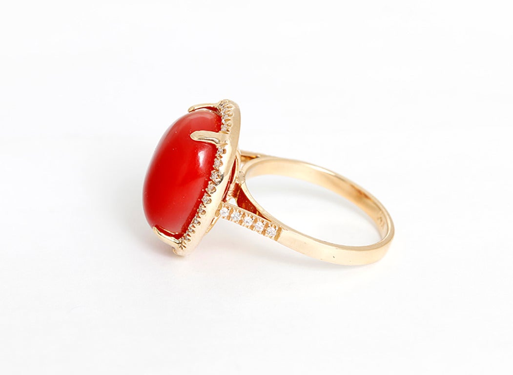This beautiful ring features an oval-shaped coral cabochon bordered by apx. 0.40 carats of diamonds  in 14k yellow gold. Ring measures apx. 15.3 x 12.7 x 9.0mm.  Total weight is 6.4 grams. Size 6-1/4.