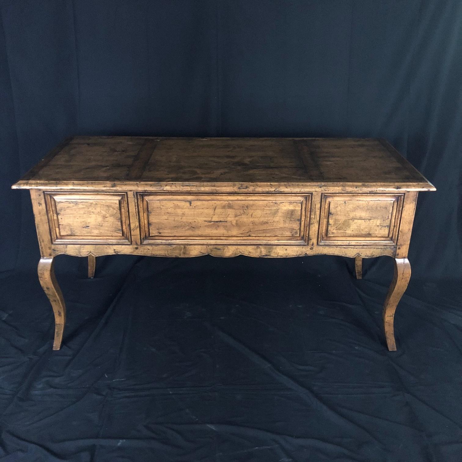 A lovely country French Provincial desk by Guy Chaddock from the Melrose Collection. The desk is made of mixed light woods featuring raised inset panels throughout, an inset paneled top and tapered cabriole legs. The desk is designed with a center