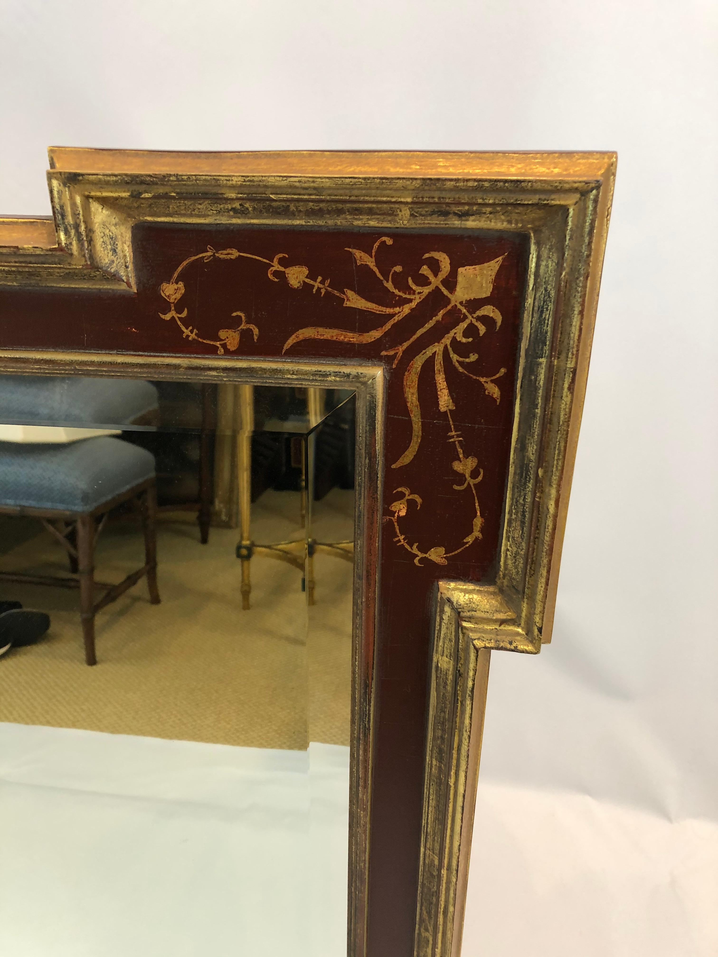 Grand et beau miroir rectangulaire avec des coins en forme de flèche ayant un cadre peint et doré à la canneberge et un miroir biseauté. Peut être orienté verticalement ou horizontalement.