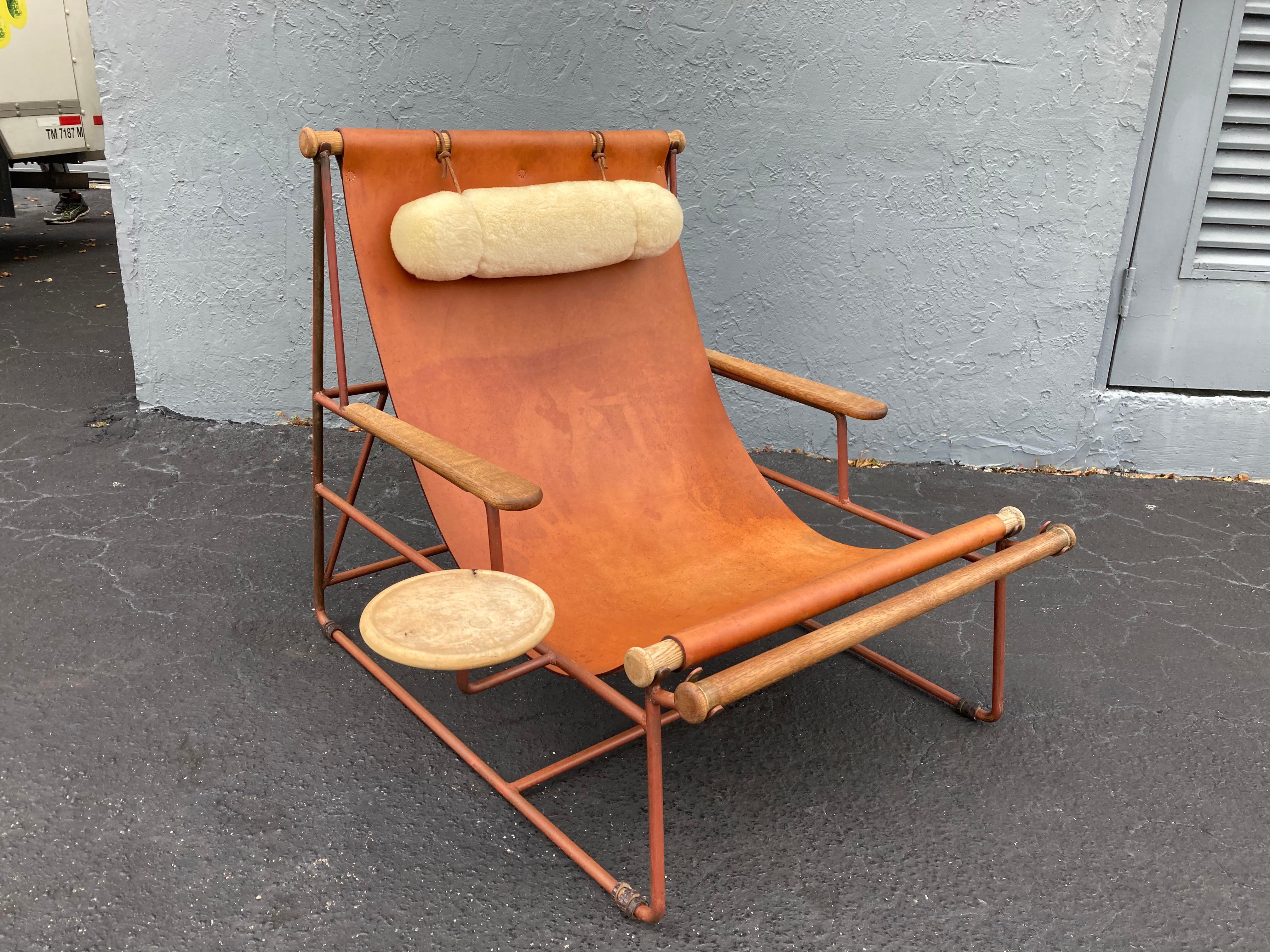 Deck lounge chair designed by Tyler Hays and made by BDDW.
The chair has a beautiful patina, bronze frame has turned reddish and leather has collected wear, comes with a shearling pillow and wood tray.
