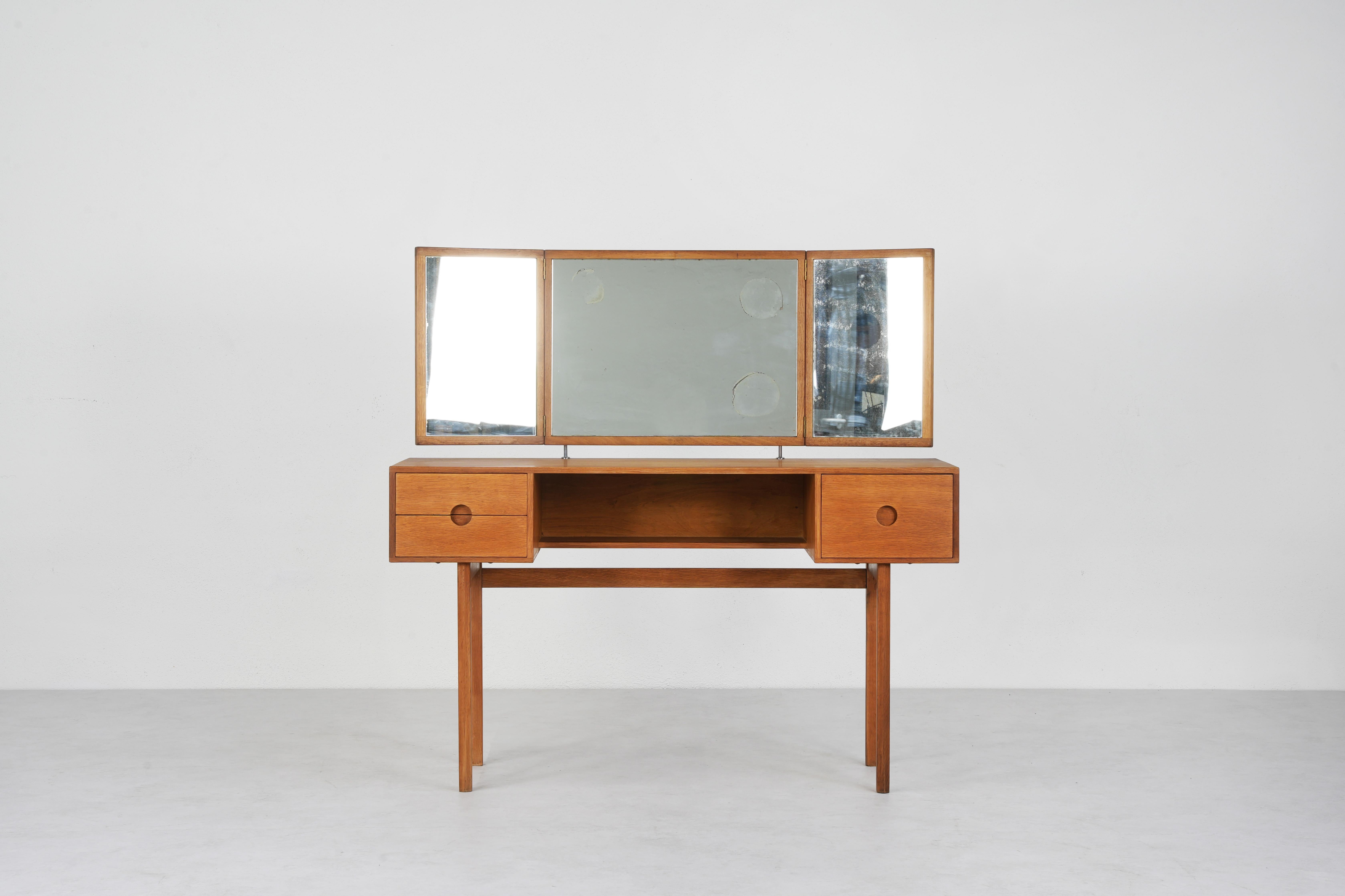 Designed by Kai Kristiansen for Aksel Kjersgaard in the mid-1960s, model 40. Solid oak drawer fronts with striking round recessed pulls. 
The mirror angle adjusts by sliding the oak cubes up and down the mounting posts (in the back).
Great condition