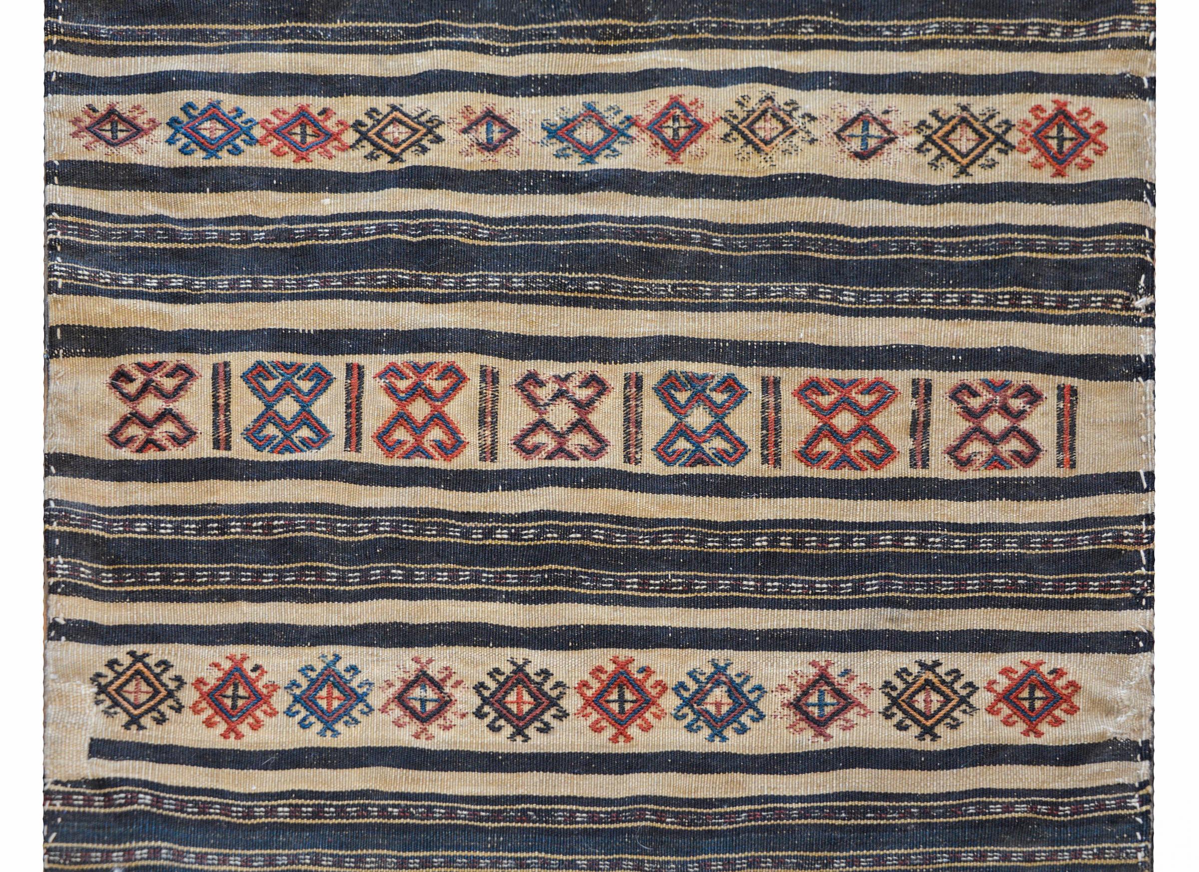 Magnifique tapis persan du début du XXe siècle, de type Afshar Grain bag face, avec un merveilleux motif rayé contenant des bandes tissées unies de couleur indigo, agrémentées de motifs brodés de couleur cramoisie, or, et indigo clair et foncé.