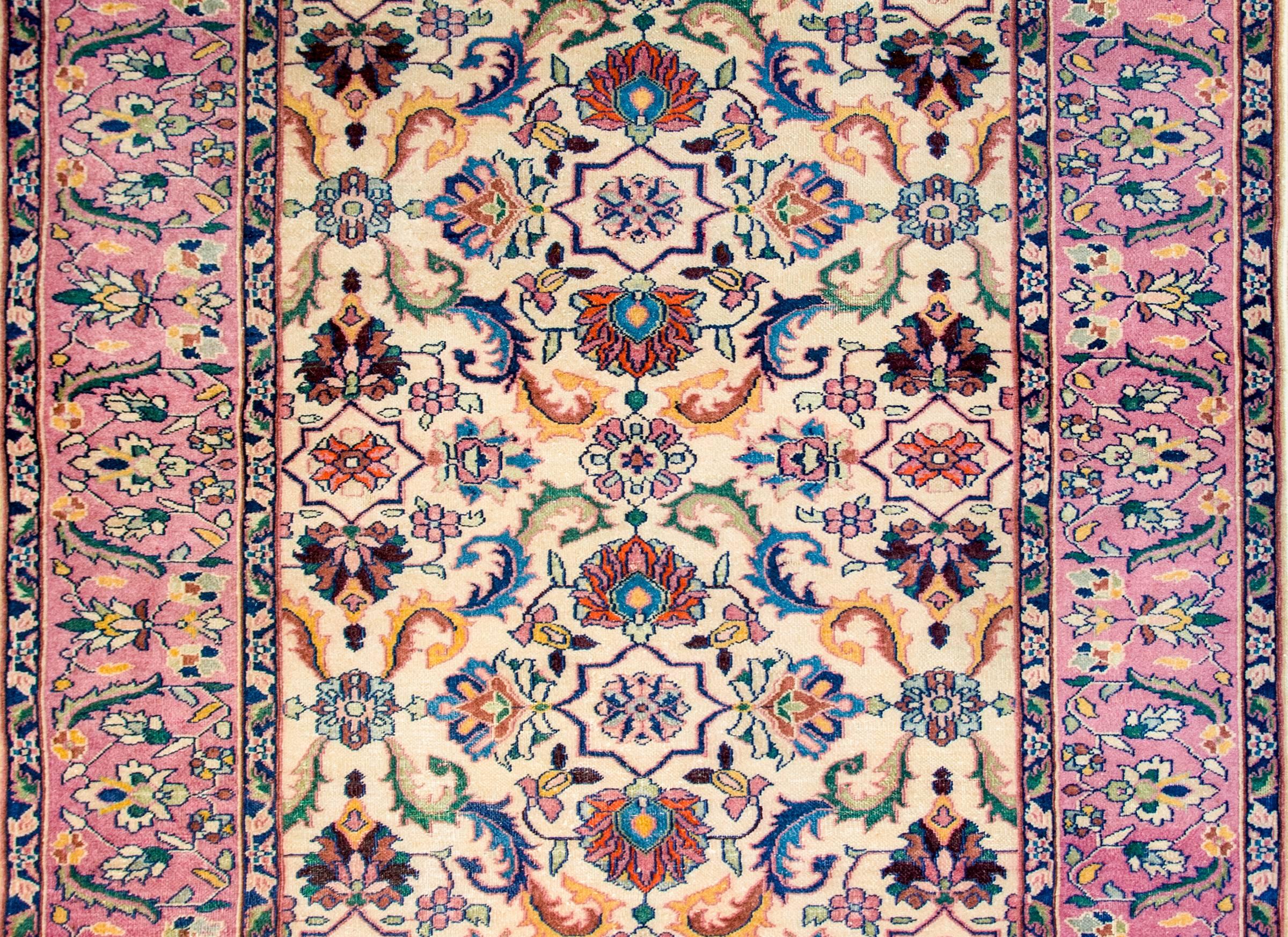 An early 20th century Indian Agra rug with a wonderful large-scale mirrored multicolored floral and vine pattern on a cream colored background. The border is wide with a central floral and vine patterned central strip flanked by matching petite