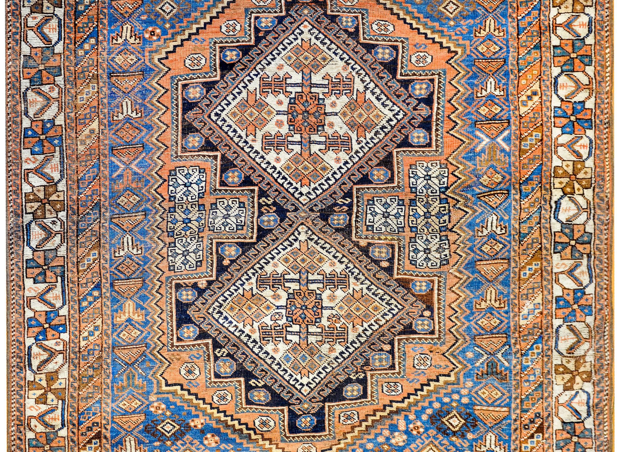An amazing early 20th century Persian Ghashgaei rug with two large diamond medallions with a floral pattern, on a wonderful field of tightly woven diamonds woven in black, indigo, orange and white colored wool. The border is fantastic with four