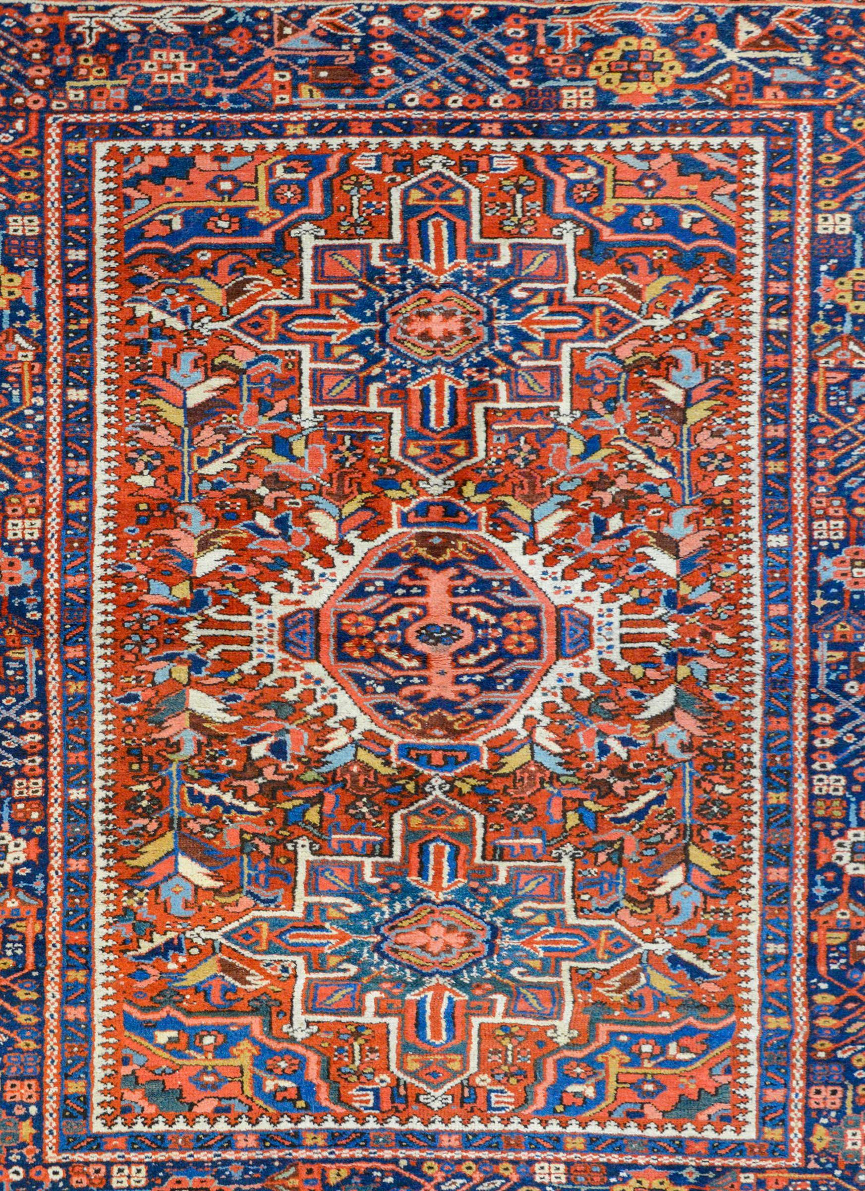 A beautiful early 20th century Persian Karajeh rug with three large medallions against an intricately woven field of myriad flowers and leaves, all woven in bright crimson, indigos, gold, green, and white colored wool. The border is equally