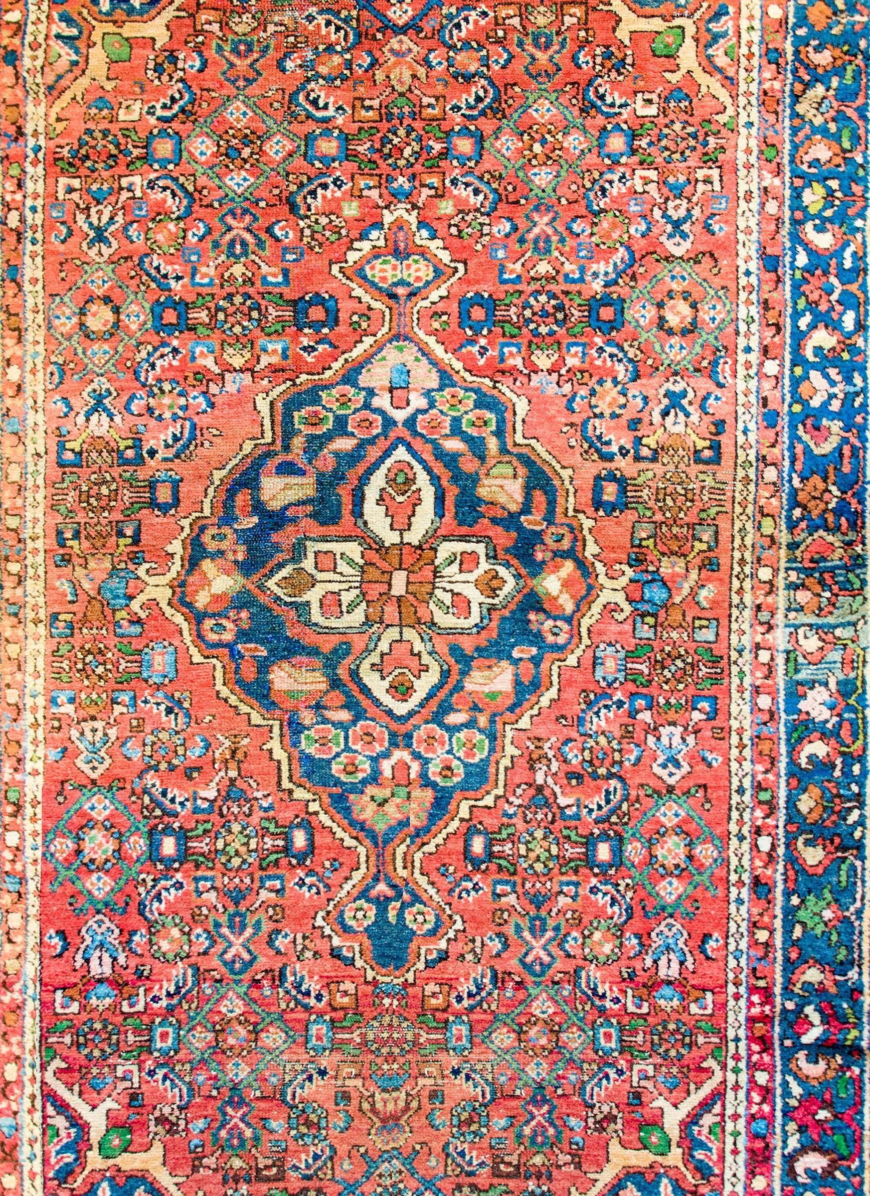 Un bellissimo tappeto persiano Malayer dell'inizio del XX secolo con un grande medaglione floreale centrale a rombi con una miriade di fiori tessuti in lana tinta al vegetale color cremisi, indaco, verde, oro e nero su un campo cremisi con