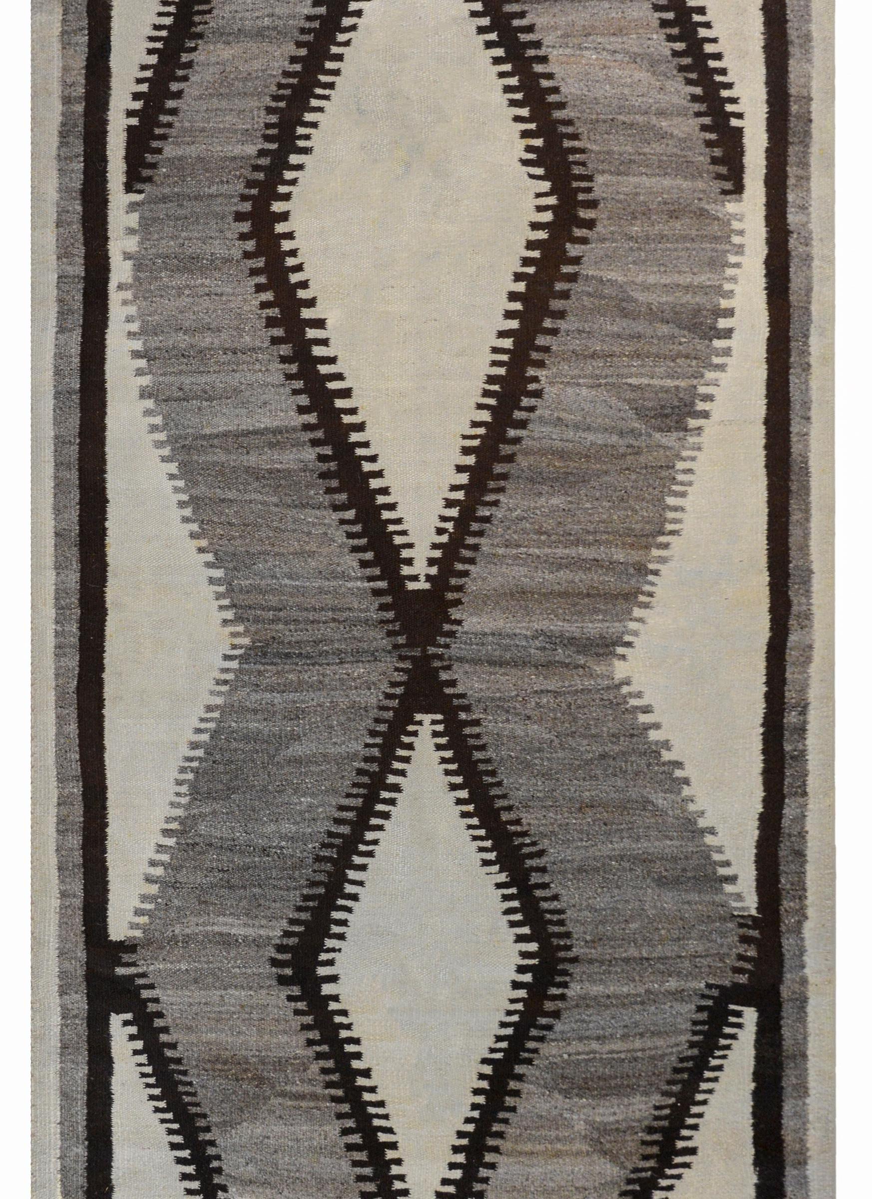 A beautiful early 20th century Navajo rug with a large-scale asymmetrical diamond pattern woven in varying shades of gray, black, and white surrounded by a solid stripe of each color.