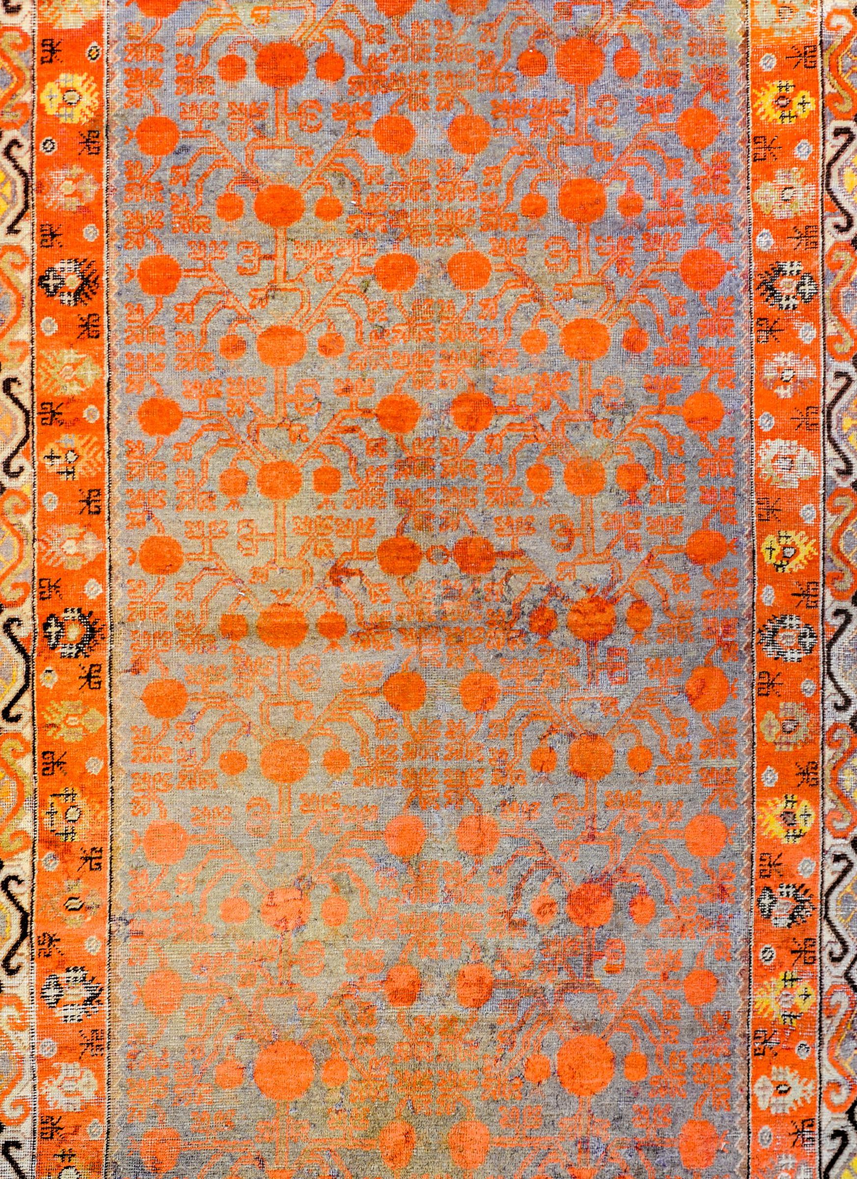 A beautiful early 20th century Central Asian Samarghand with a traditional all-over trellis pomegranate pattern woven in orange colored wool on a faded indigo ground. The border is wonderful with a stylized tree-of-life inner stripe and a wide outer