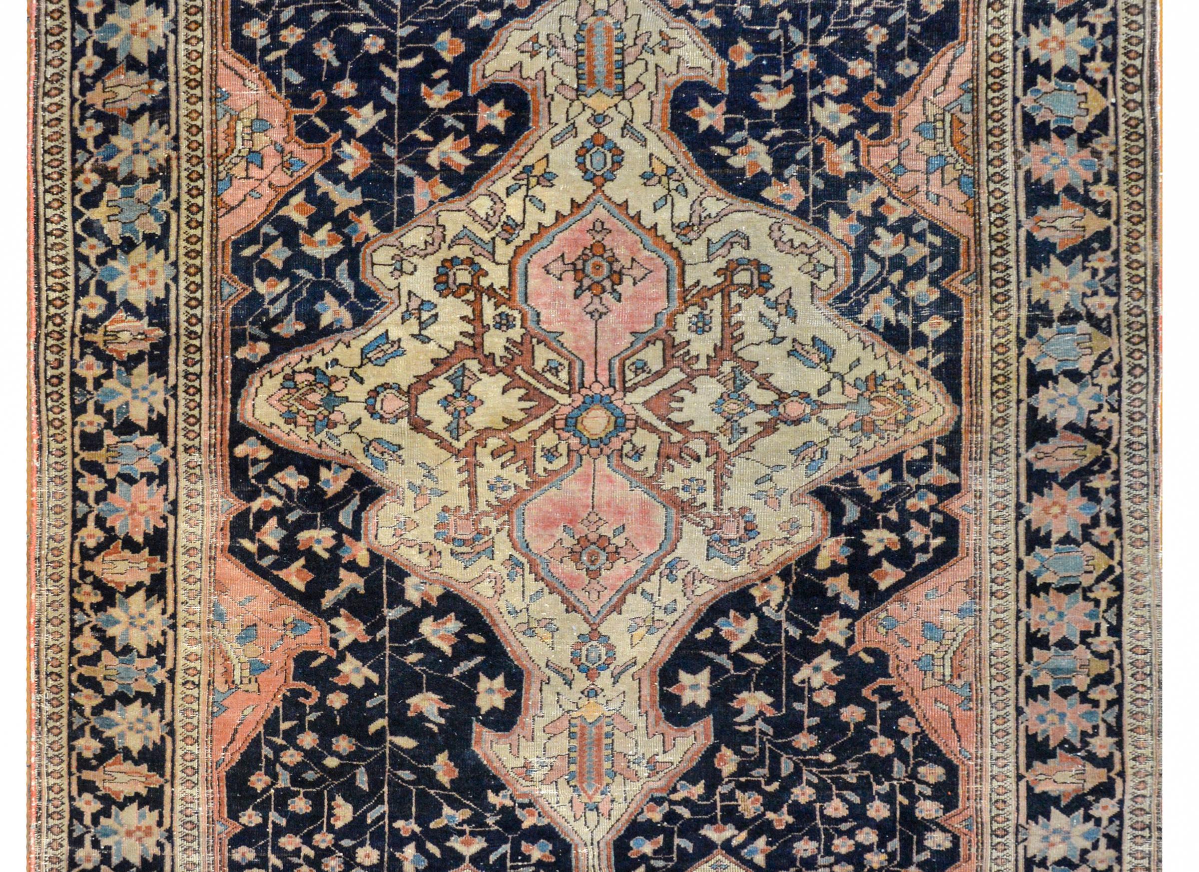 A beautiful early 20th century Sarouk Farahan rug with a multi-lobed medallion with a floral and scrolling vine pattern woven in dark red, indigo, gold, and brown vegetable dyed wool on a cream colored background, amidst an indigo field of flowers