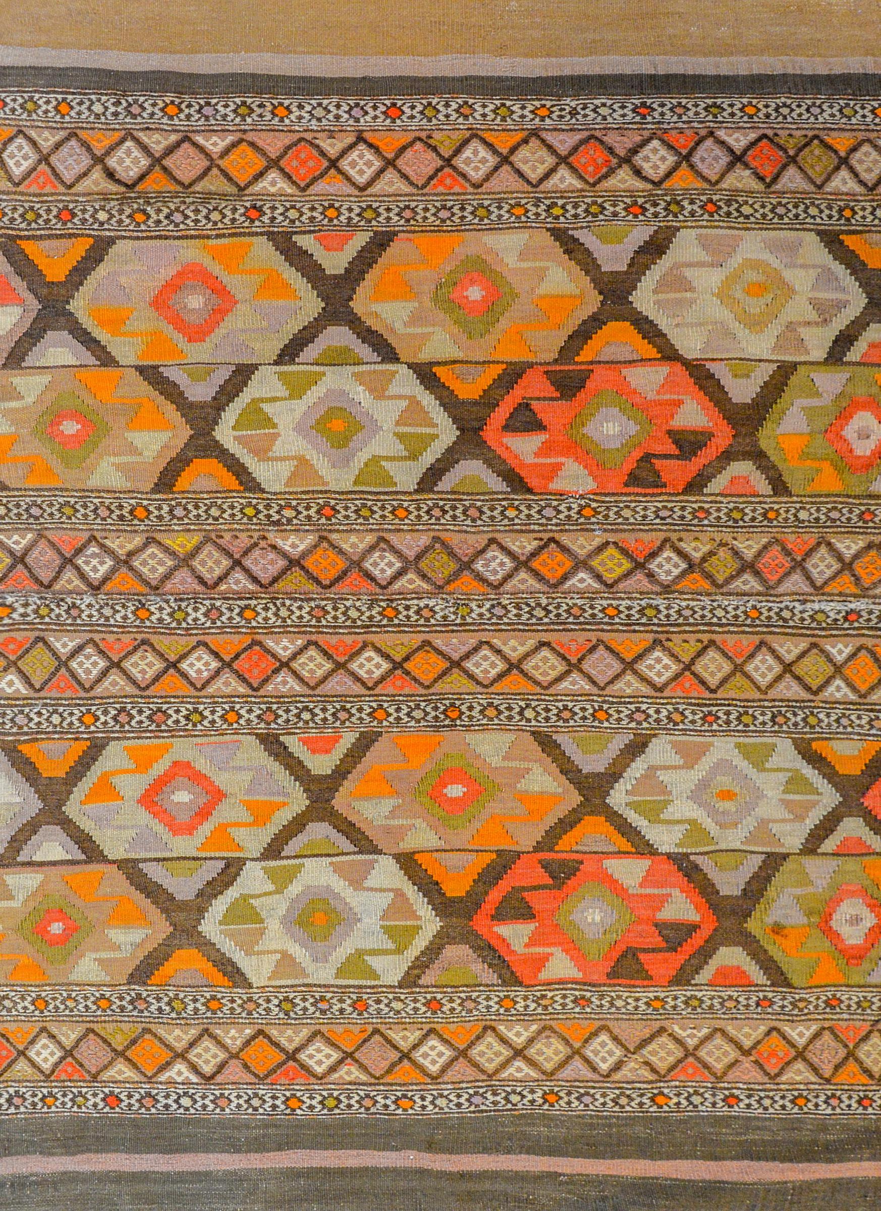 A beautiful early 20th century Persian Shahsevan Kilim rug with a wonderful bold geometric pattern of stylized flowers woven in coral, orange, green, white and brown vegetable dyed wool with thinner strips of hand-embroidered trellis and geometric