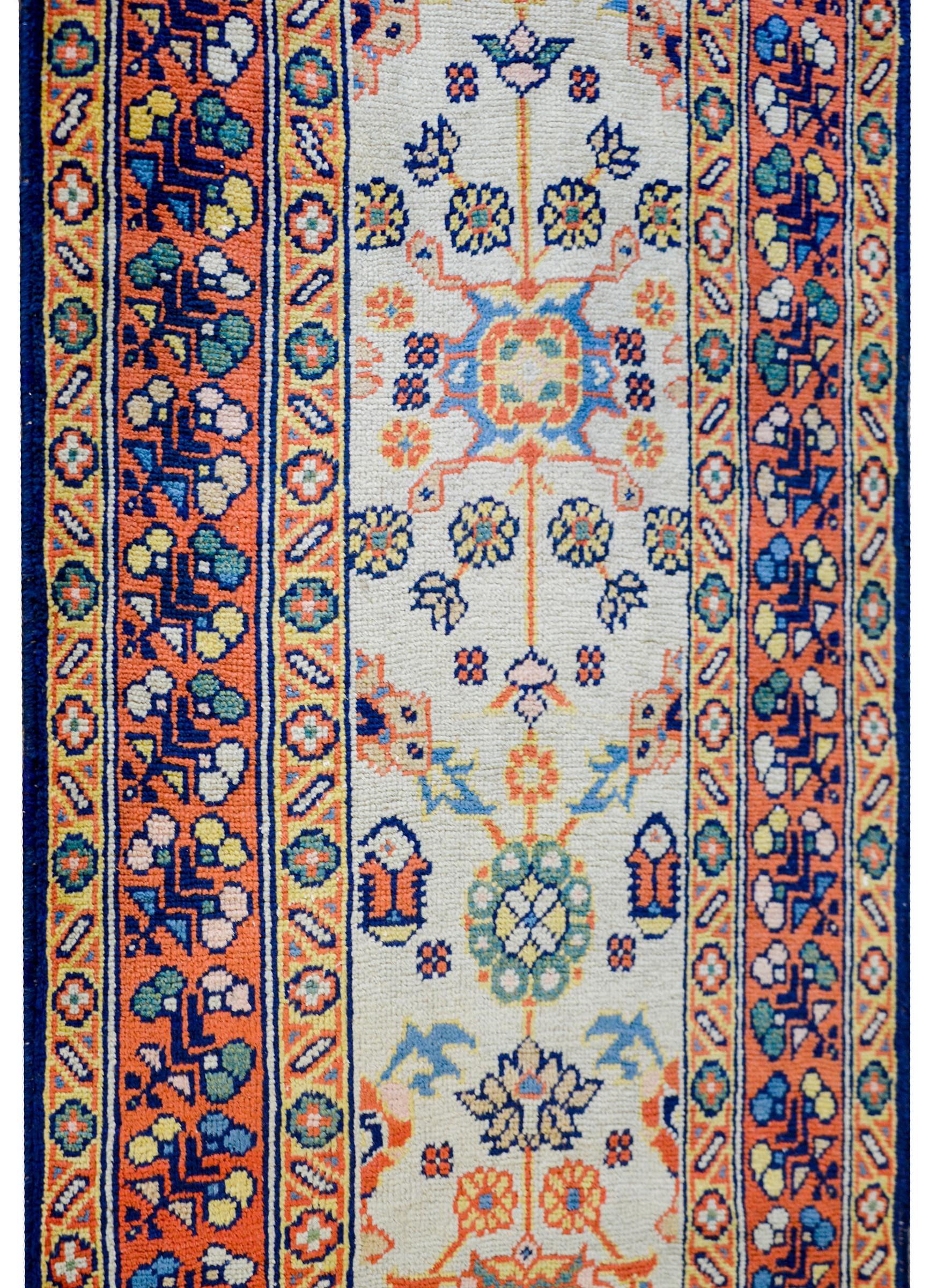 An early 20th century Persian Sultanabad runner with a fantastic all-over multicolored floral pattern woven in crimson, green, indigo, and gold, on a white background. The border is beautiful with a wide central floral patterned stripe with a