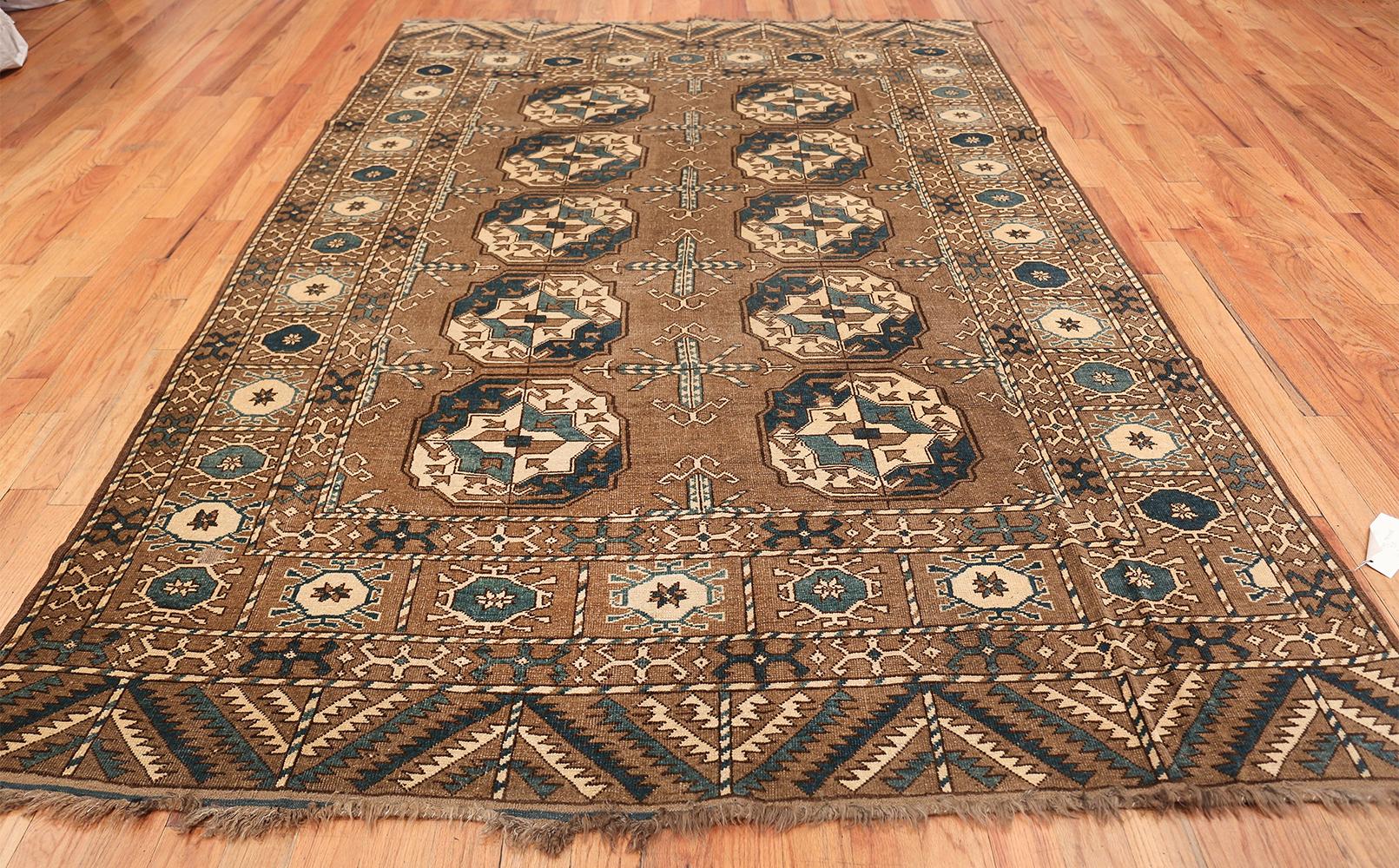 Beautiful and decorative earthtone antique Afghan rug, Country of origin: Afghanistan, circa date: First Quarter of The 20th century. Size: 6 ft 7 in x 9 ft 7 in (2.01 m x 2.92 m). With an earthy central palette and plenty of angular figures within,