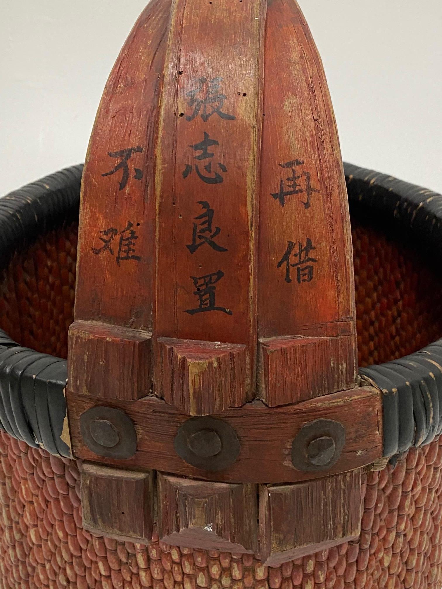 Ein wunderschöner chinesischer Marktkorb aus geflochtenem Rattan mit dekorativen Schriftzügen auf dem hölzernen Griff und einer tollen rötlichen Patina.