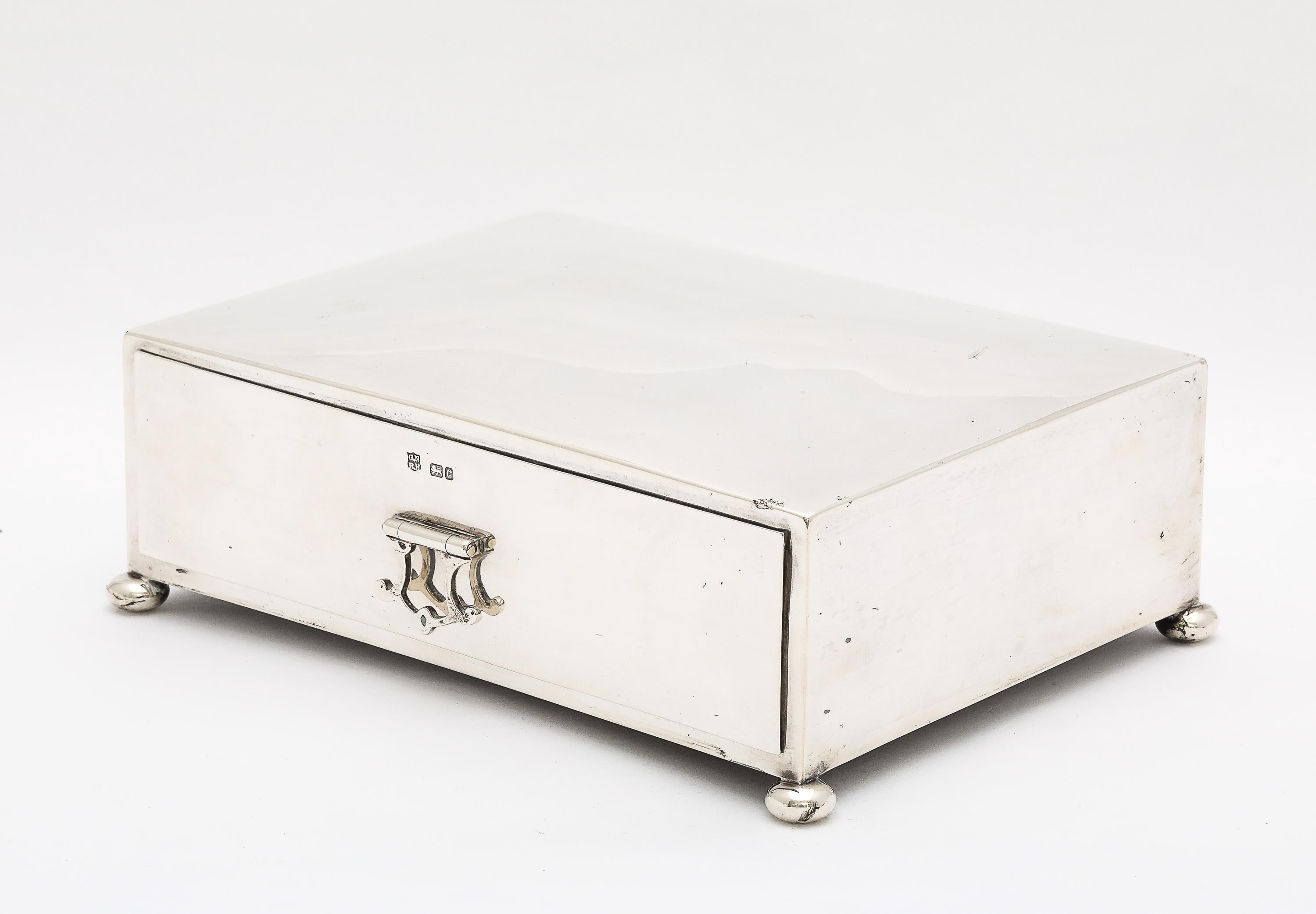 Precioso joyero-mesa de plata de ley de la época eduardiana, con patas de bola,  con una tapa abatible y un cajón extraíble (que tiene un bonito tirador abatible). La caja se fabricó en Chester (Inglaterra) y lleva la marca del año 1903, George
