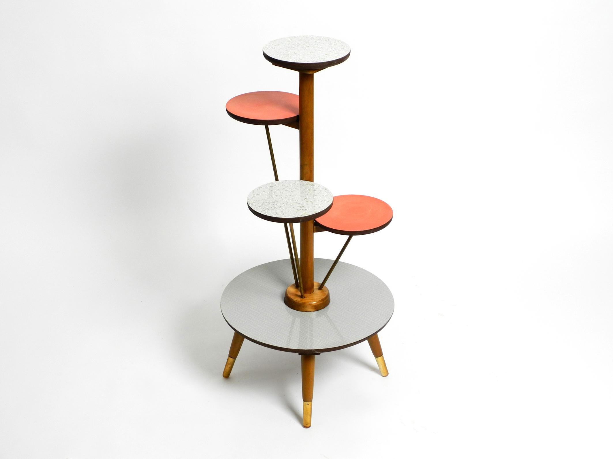Beautiful extraordinary large four-legged Mid-Century Modern plant stand.
Great typical design of that time. Made in Germany.
Frame and all round and colored shelves are made of wood with colorful Formica surfaces.
The wooden legs are partly