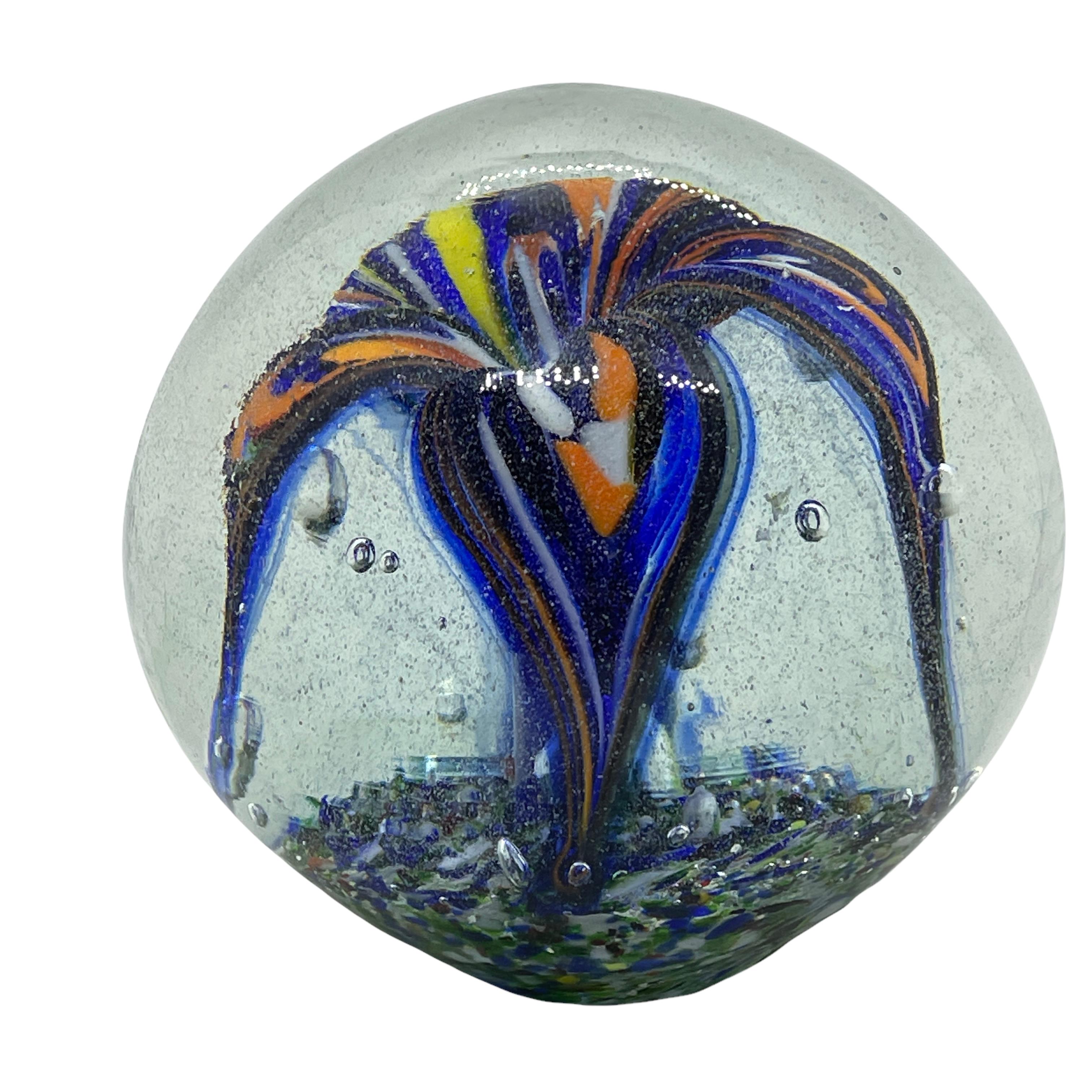 Beautiful Murano hand blown Italian art glass paper weight. Showing a flower inside, in different colors, floating on controlled bubbles. Colors are a green, orange, yellow, blue, black and white. A beautiful nice addition to your desktop.