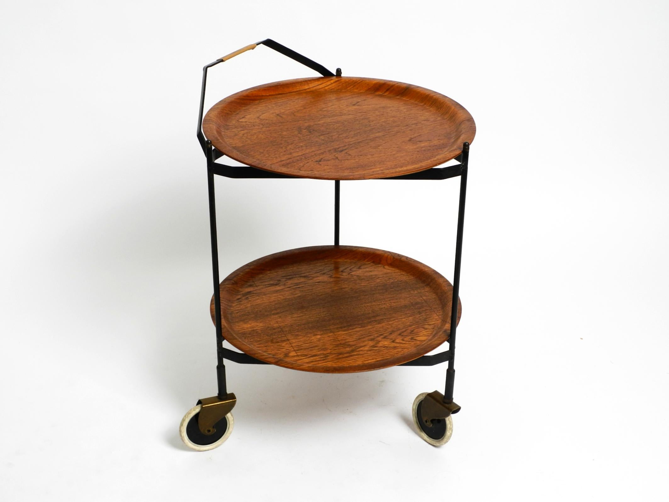 Beautiful folding Mid-Century Modern serving cart.
Also great as a side table.
With removable round teak pagwood trays.
Frame is made of black lacquered metal.
All three wheels roll and rotate smoothly.
No damage to the frame. No rust and original