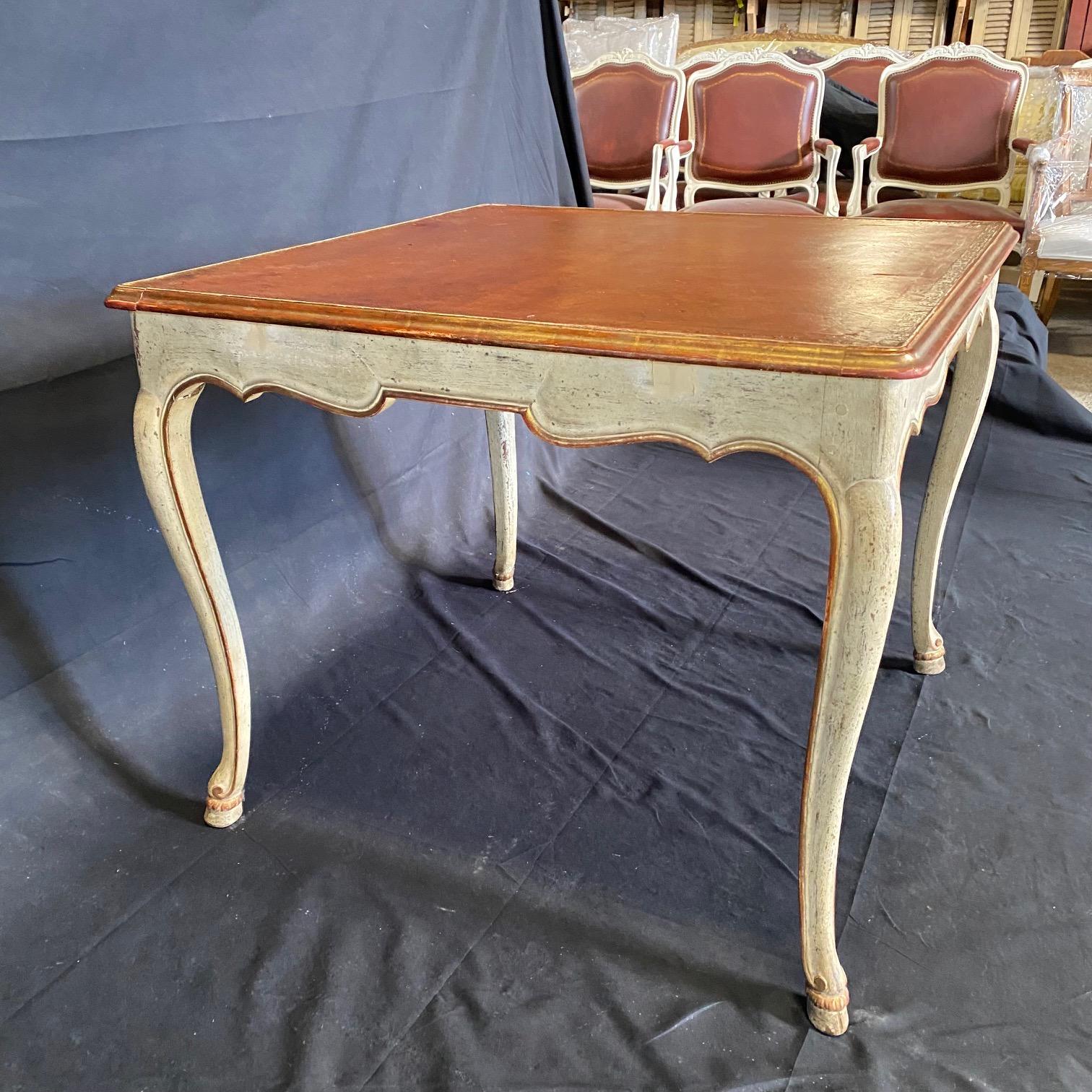 Antique French walnut leather top table was sculpted from fine French walnut, the contoured and beveled top which is square, frames a lovely brown leather surface with tooled gold bordering. The relatively shallow apron over four gracefully carved