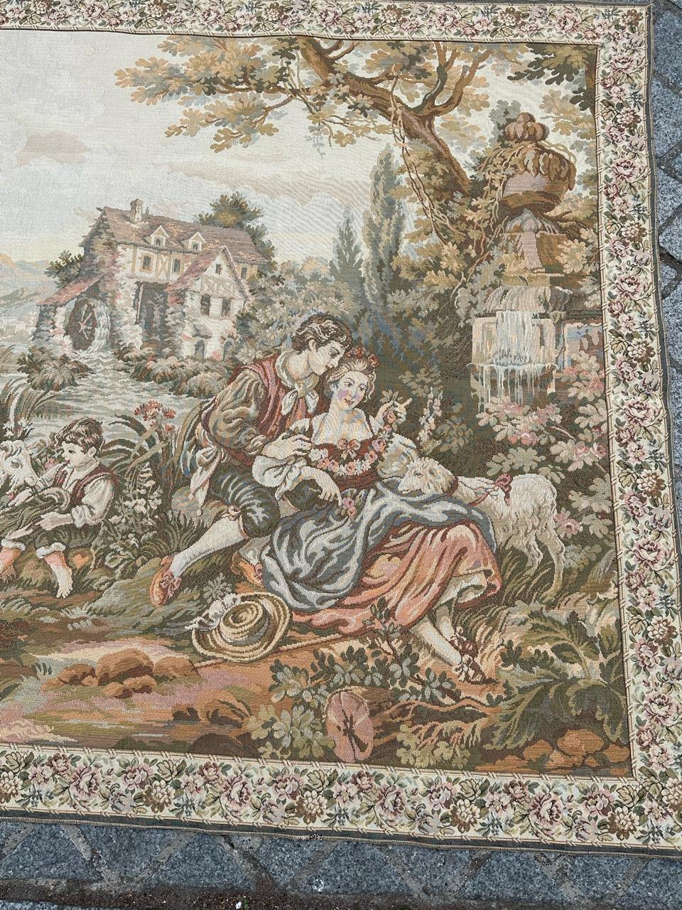 Elevate your space with a charming French tapestry featuring a gallant village scene. Woven with precision on Jacquard looms in France, this masterpiece showcases couples by the river, playful children, and adorable animals like lambs, goats, and a