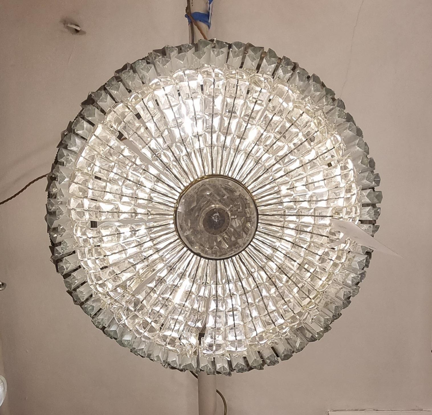 A beautiful decorative plafonnier suitable for modern housing as it fits close to the ceiling and gives a beautiful spread of light from its 9 internal bulbs. The silver coloured frame is surrounded by crystal stars affixed to the upper tier from
