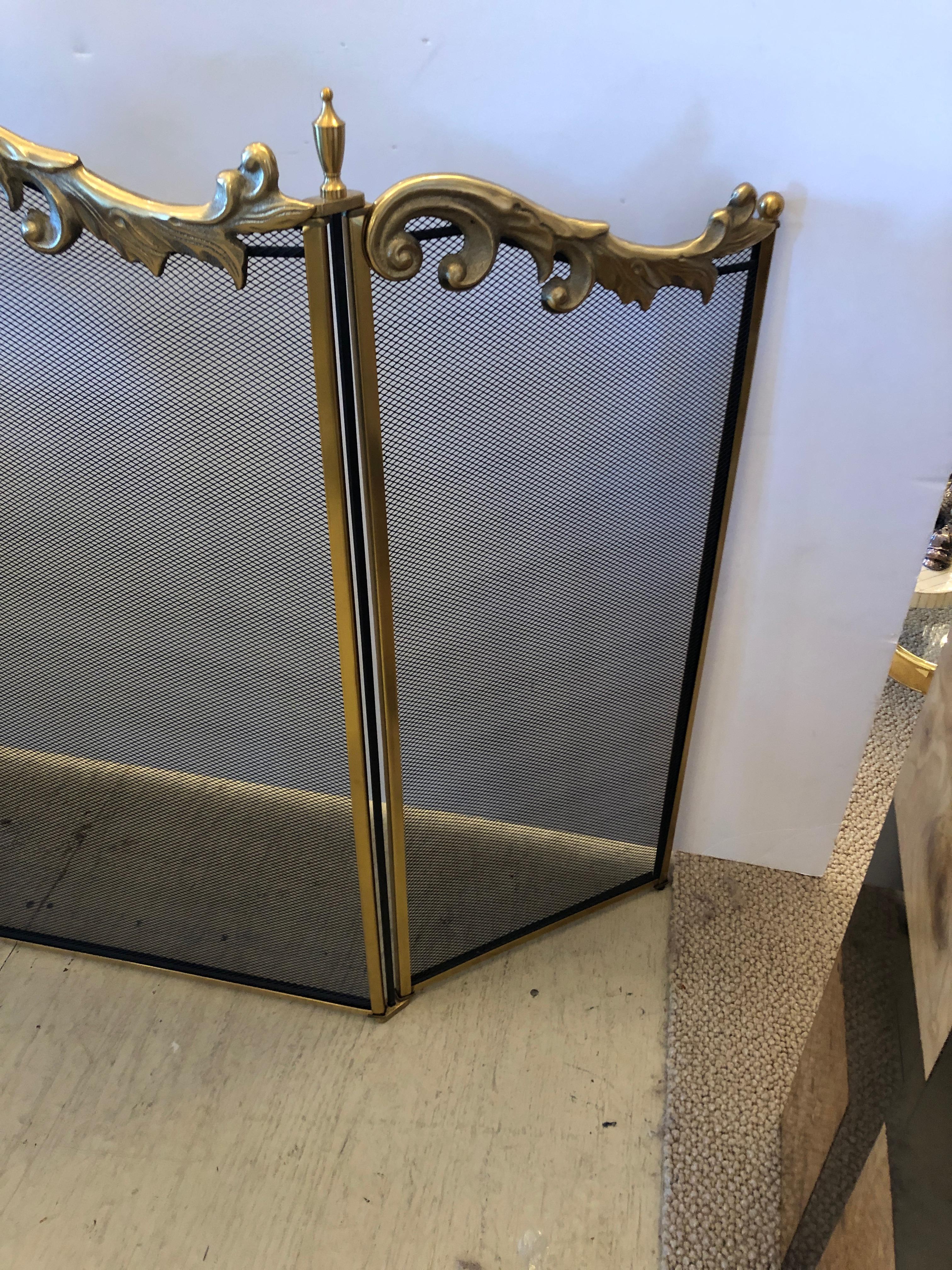 Heavy black iron and mesh fireplace screen having beautiful flourish at the top of scalloped brass decoration including urns and ball finials.