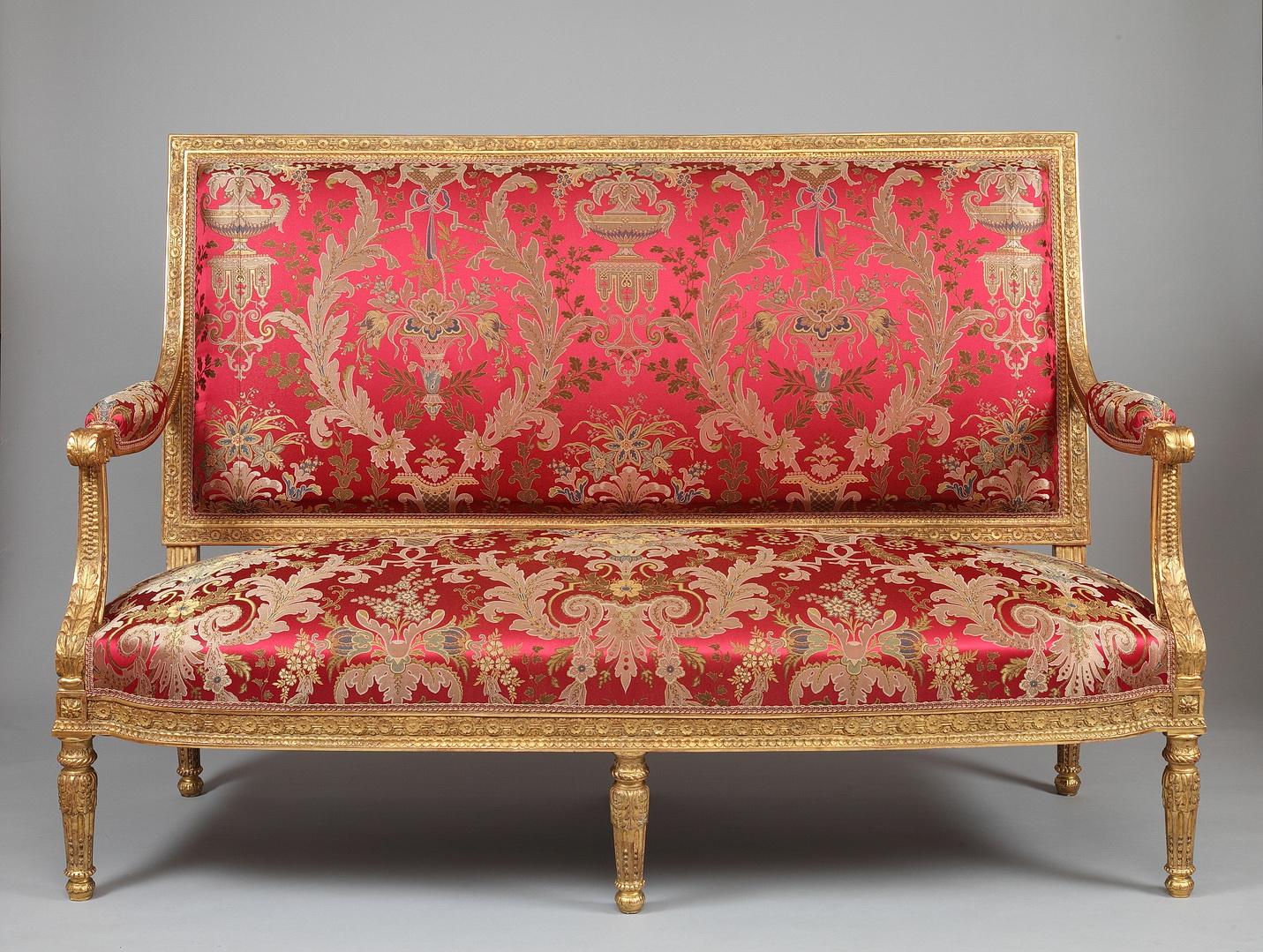 Richly carved giltwood sofa, upholstered with a Tassinari & Chatel red silk ornamented with flowers and central medallions, imagined after the 1788 model made by G. Jacob for the Castle St Cloud.