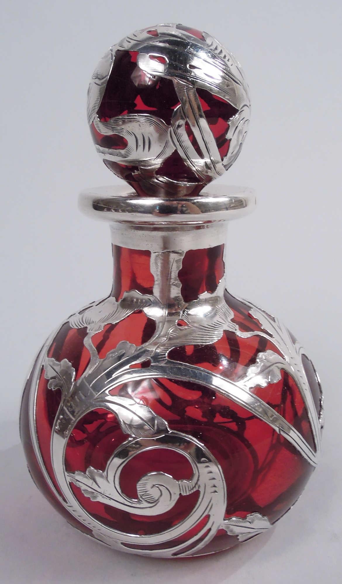 Beautiful Art Nouveau Classical glass perfume with silver overlay, ca 1900. Globular bottle with short neck and ball stopper. Classical flowering and leafing rinceaux overlay with round frame (vacant). Glass is red. Silver has maker’s stamp (Gorham)