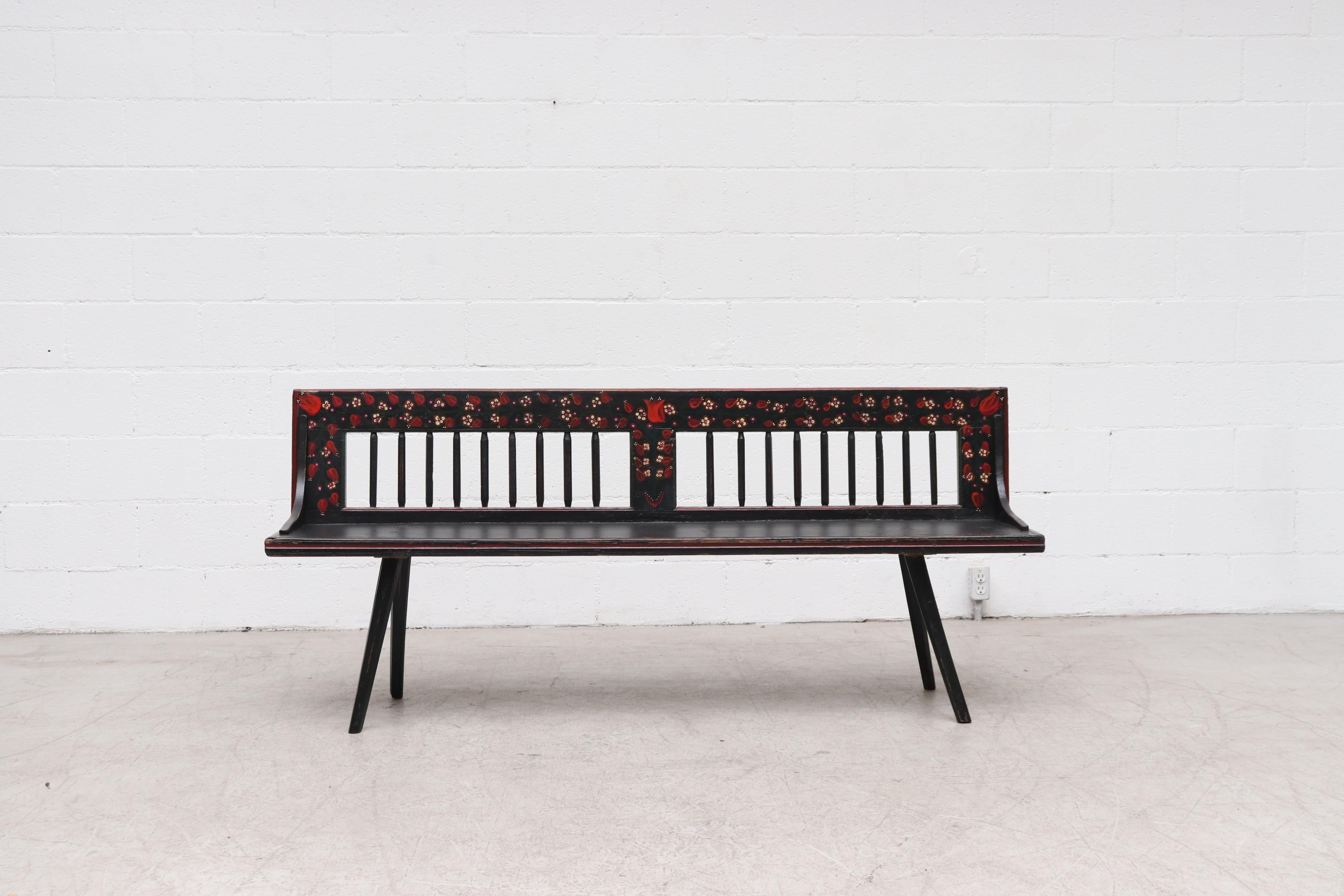 Handsome midcentury Dutch spindle back wood bench with hand painted black wood and ornate flower decoration. In very original condition with wear and scratches consistent with its age and use.