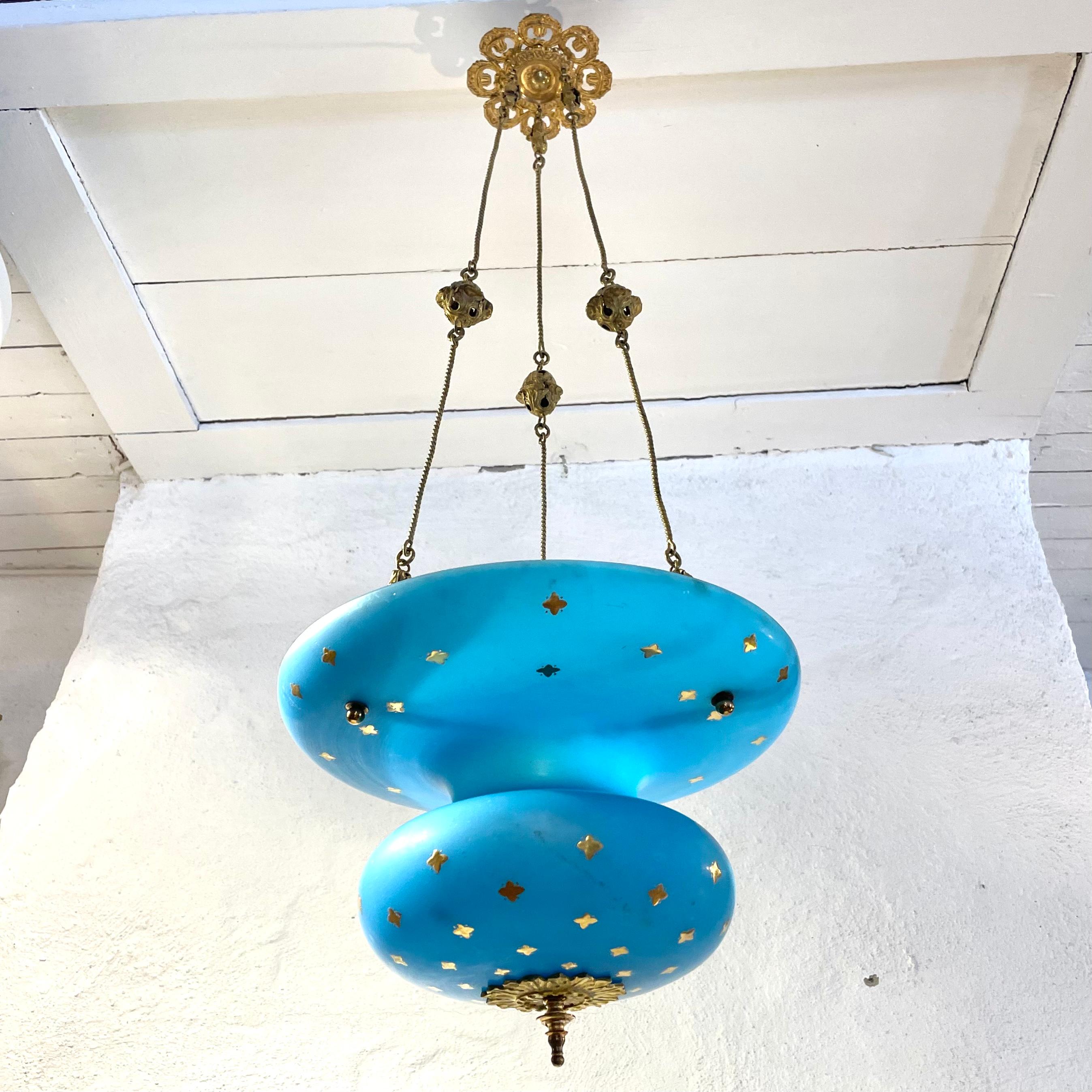 Beautiful hanging chandelier for a candle in opaline glass from the 1840s. Very cool color on the opaline glass with details in brass and gilded flowers.

The chandelier has never been electrified, only the original candle holder in the